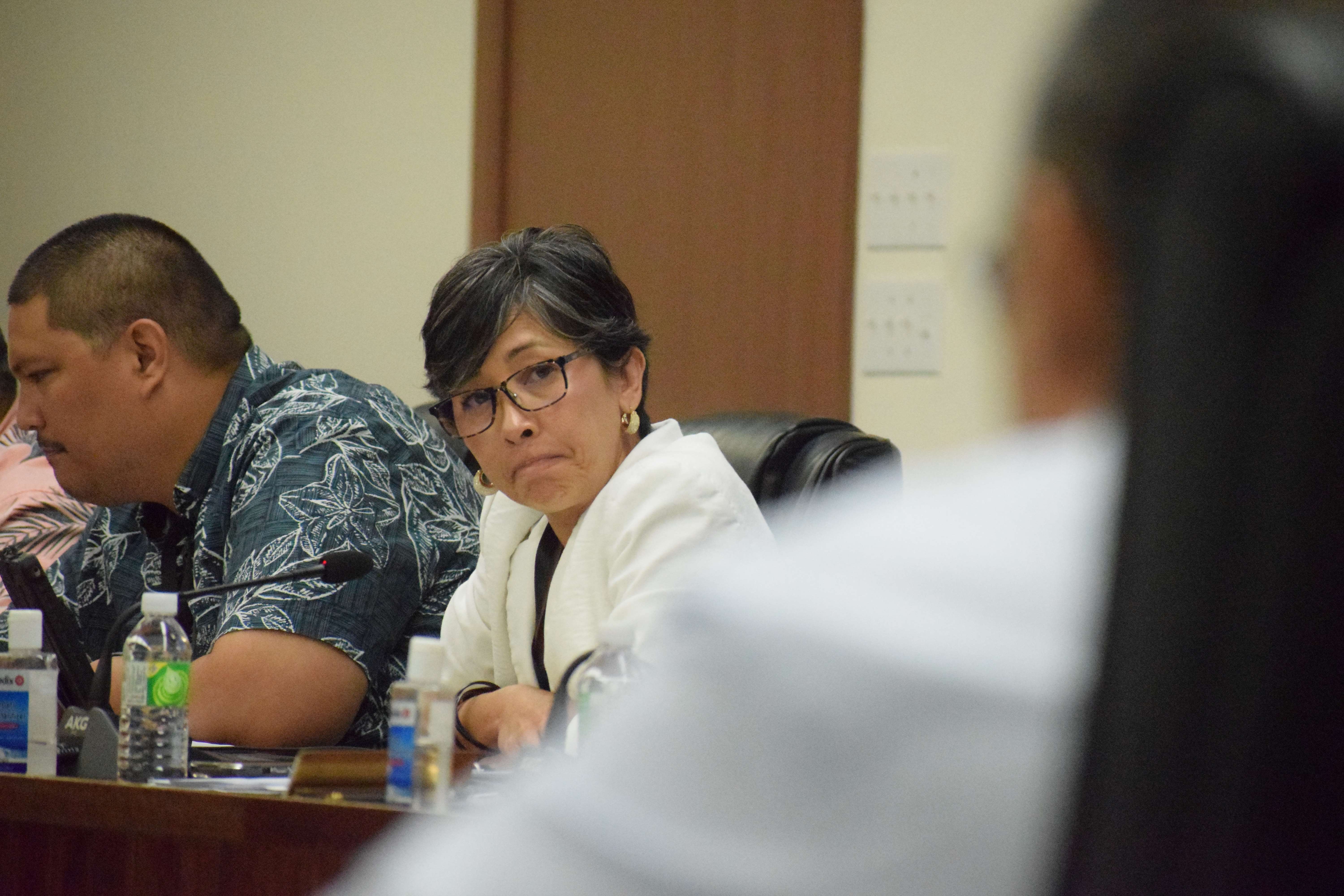 Rep. Marissa Flores listens to former Finance Secretary David DLG Atalig, back to the camera, as he invokes his Fifth Amendment right.