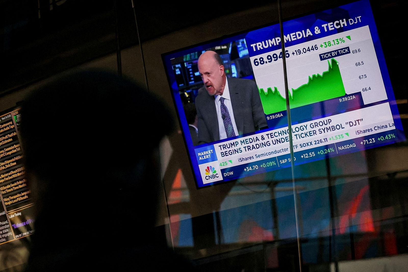 A man looks at a screen that displays trading information about shares of Truth Social and Trump Media & Technology Group, outside the Nasdaq Market site in New York City,  March 26, 2024.