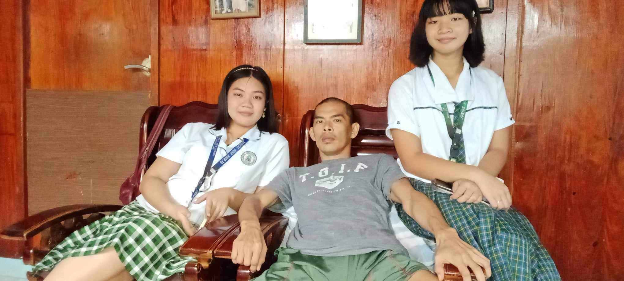 Juliana Rivera, left, and Kasandra Rivera, right, pose for a picture with their father, Jesse Rivera, in the Philippines, where the sisters are attending high school. Rivera's aunt provides care for him, while his wife, Sharolyn Alvarez, who works on Saipan, sends funds for his support.