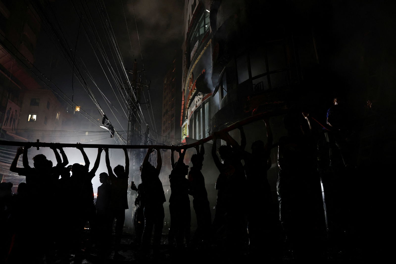 Volunteers hold a water pipe after a fire broke out in a multi-storey building in Dhaka, Bangladesh, February 29, 2024. 