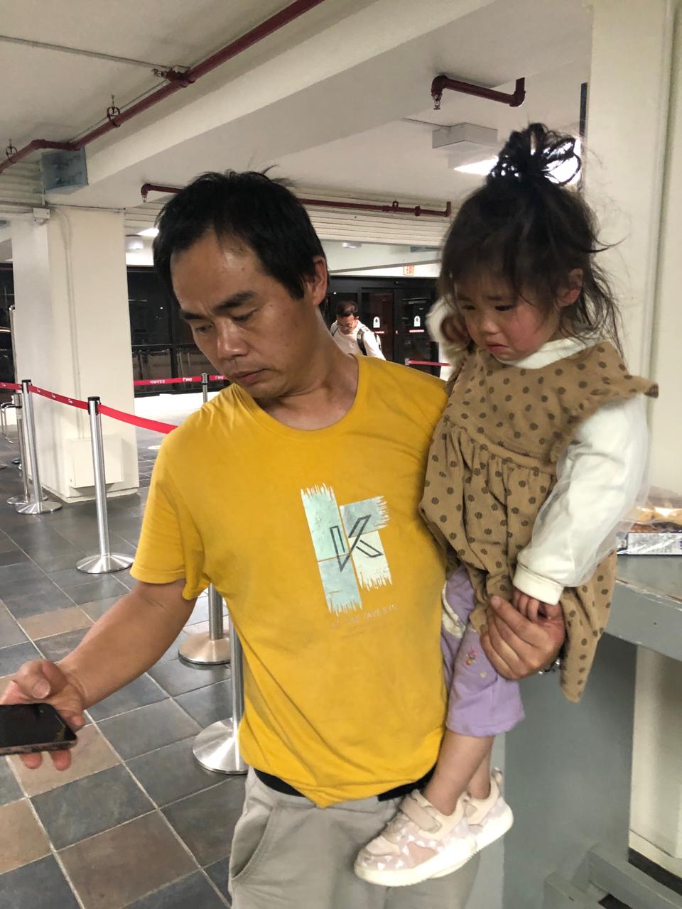 Xu Yuejun tries to make a call as daughter Ziyu cries.