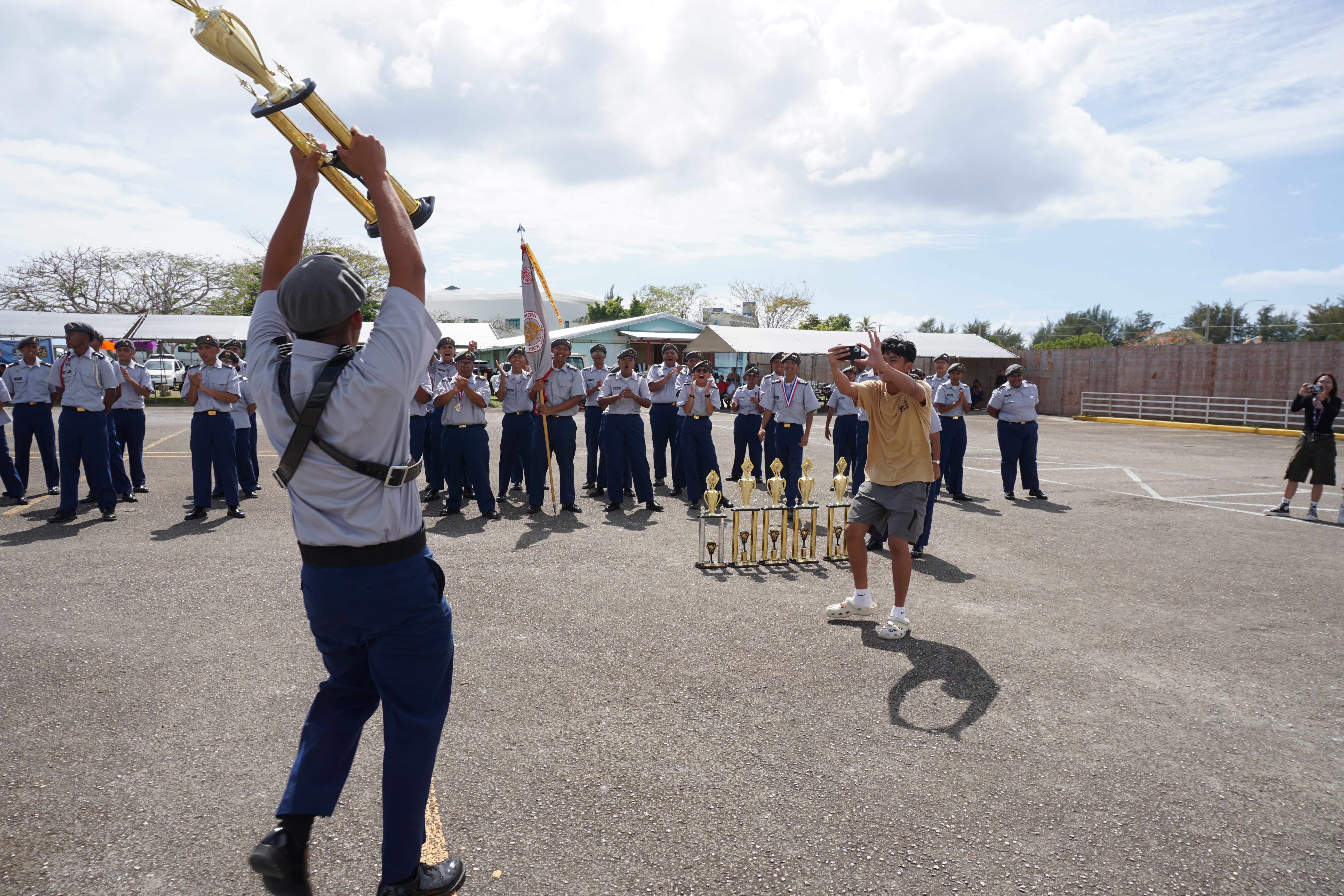 A JROTC cadet from Saipan Southern High School triumphantly returns to his classmates holding a trophy. SSHS won numerous awards, including the overall category of the unarmed drill division.