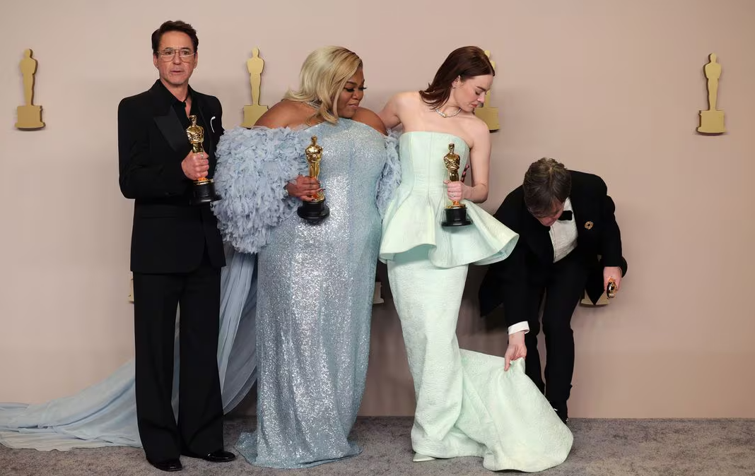 Cillian Murphy, winner of the Best Actor Oscar for "Oppenheimer," adjusts the dress of Emma Stone, winner of the Best Actress Oscar for "Poor Things," as they pose with Da'Vine Joy Randolph, Best Supporting Actress Oscar winner for "The Holdovers," and Robert Downey Jr., Best Supporting Actor Oscar winner for "Oppenheimer," in the Oscars photo room at the 96th Academy Awards in Hollywood, Los Angeles, California, March 10, 2024.