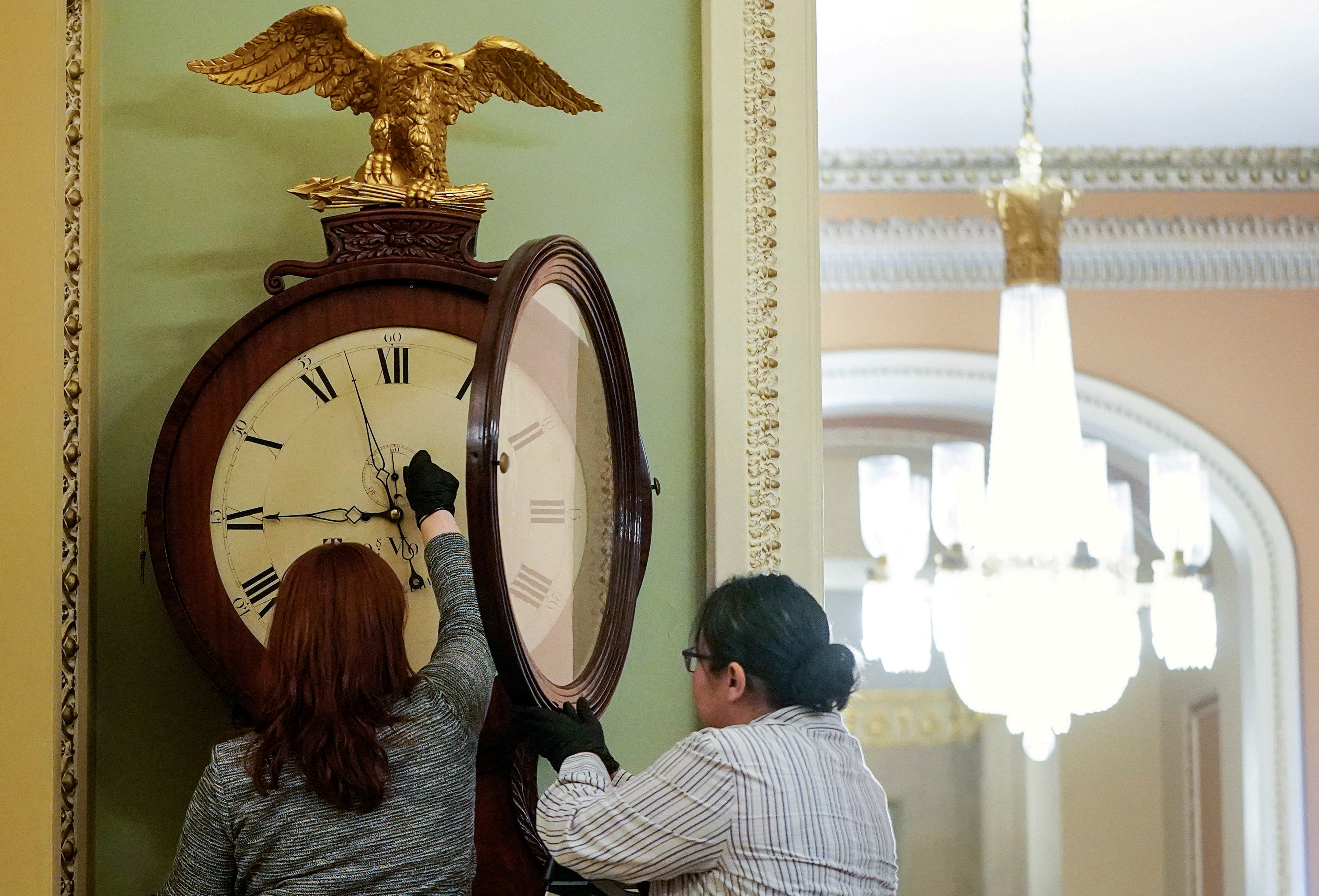 FILE PHOTO: Employees with the Architect of the Capitol wind the Ohio Clock on Capitol Hill in Washington, U.S., January 21, 2020. 