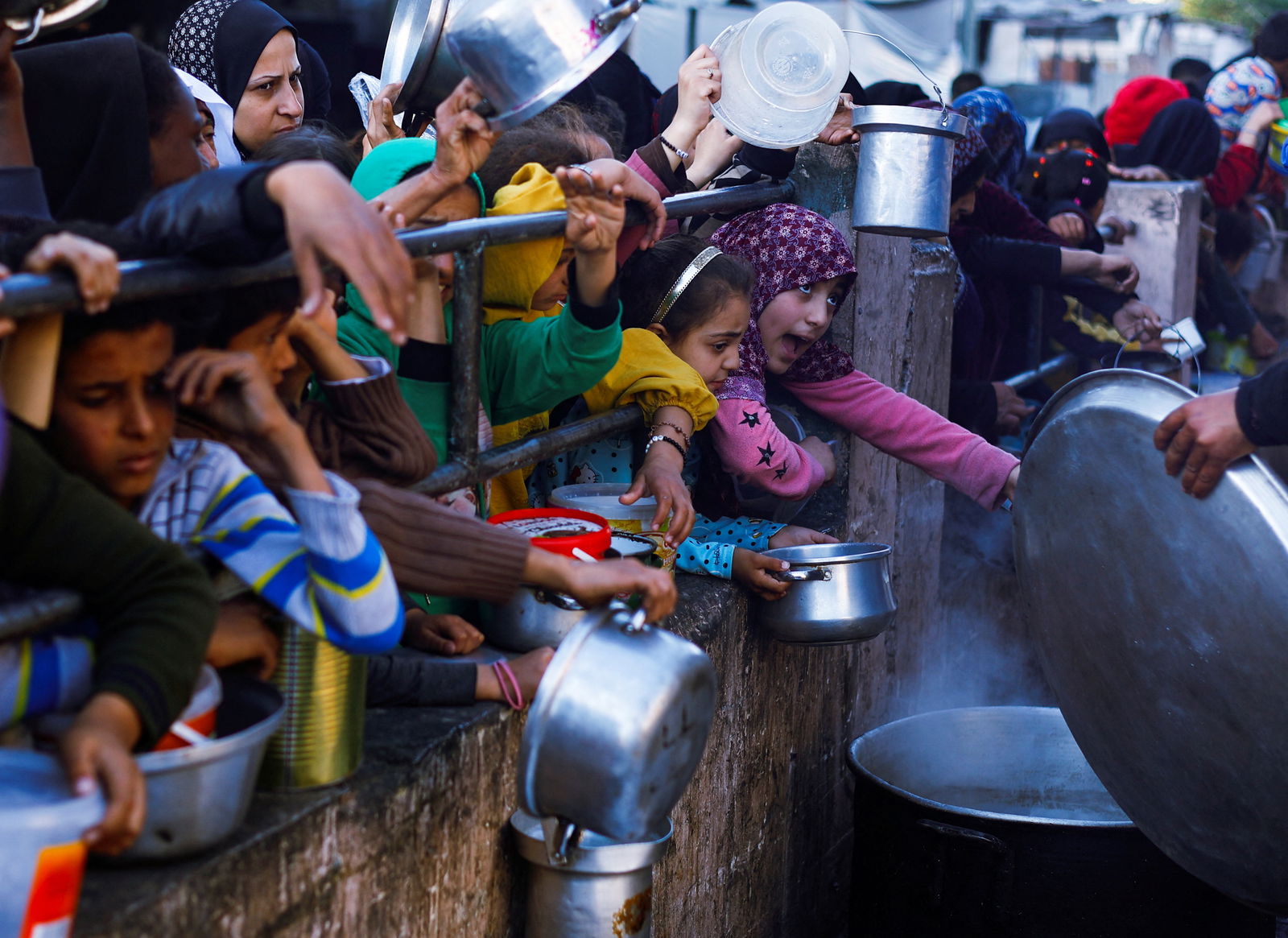 Palestinian children wait to receive food during the Muslim holy fasting month of Ramadan, as the conflict between Israel and Hamas continues, in Rafah, in the southern Gaza Strip March 13, 2024. 