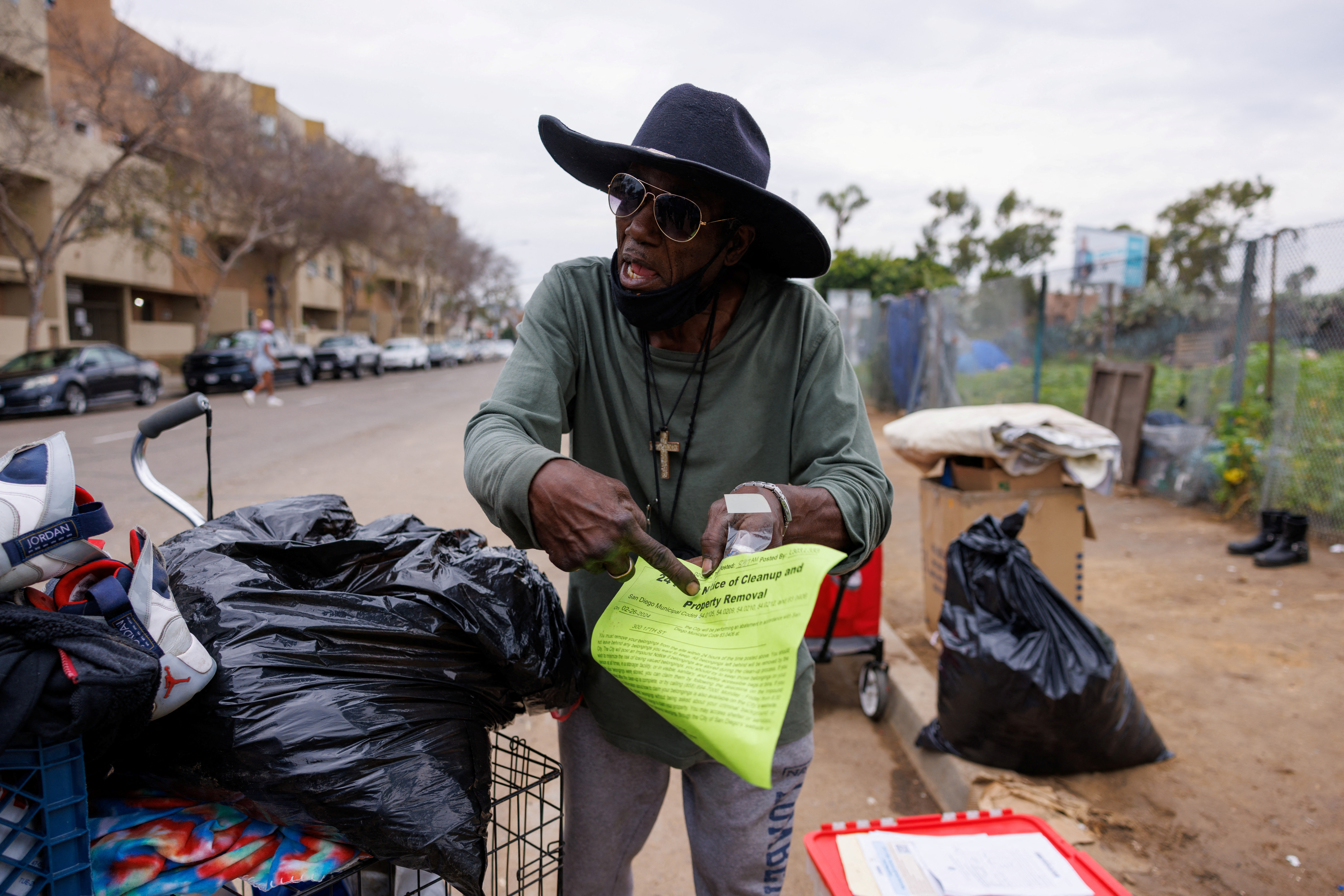 Homeless man Clarence Shine points to an eviction noticed placed on his tent by the city of San Diego a day earlier, forcing him to move out of his current location and onto state land along the freeway in downtown San Diego, California, U.S., February 26, 2024.