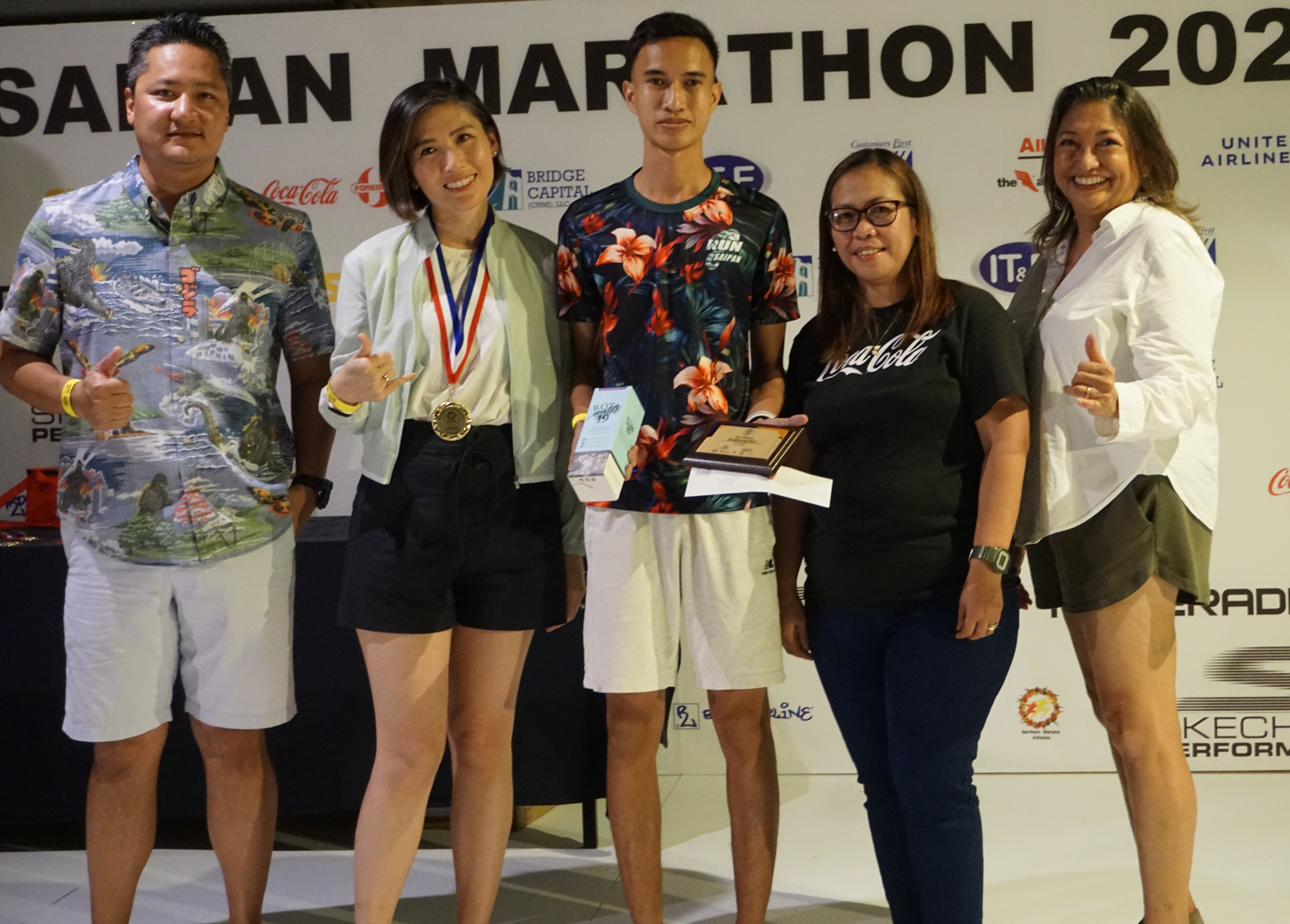 Sildrey Veloria, center, holds his 1st place plaque and other prizes for topping the 10K event of the Saipan Marathon as he poses for a photo with Marianas Visitors Authority Managing Director Christopher Concepcion, Skechers representative Jennifer Tan, Coca-Cola representative Aileen Benavidez and MVA acting Chair Gloria Cavanagh during the awards banquet at the Hyatt Regency Saipan on Saturday.