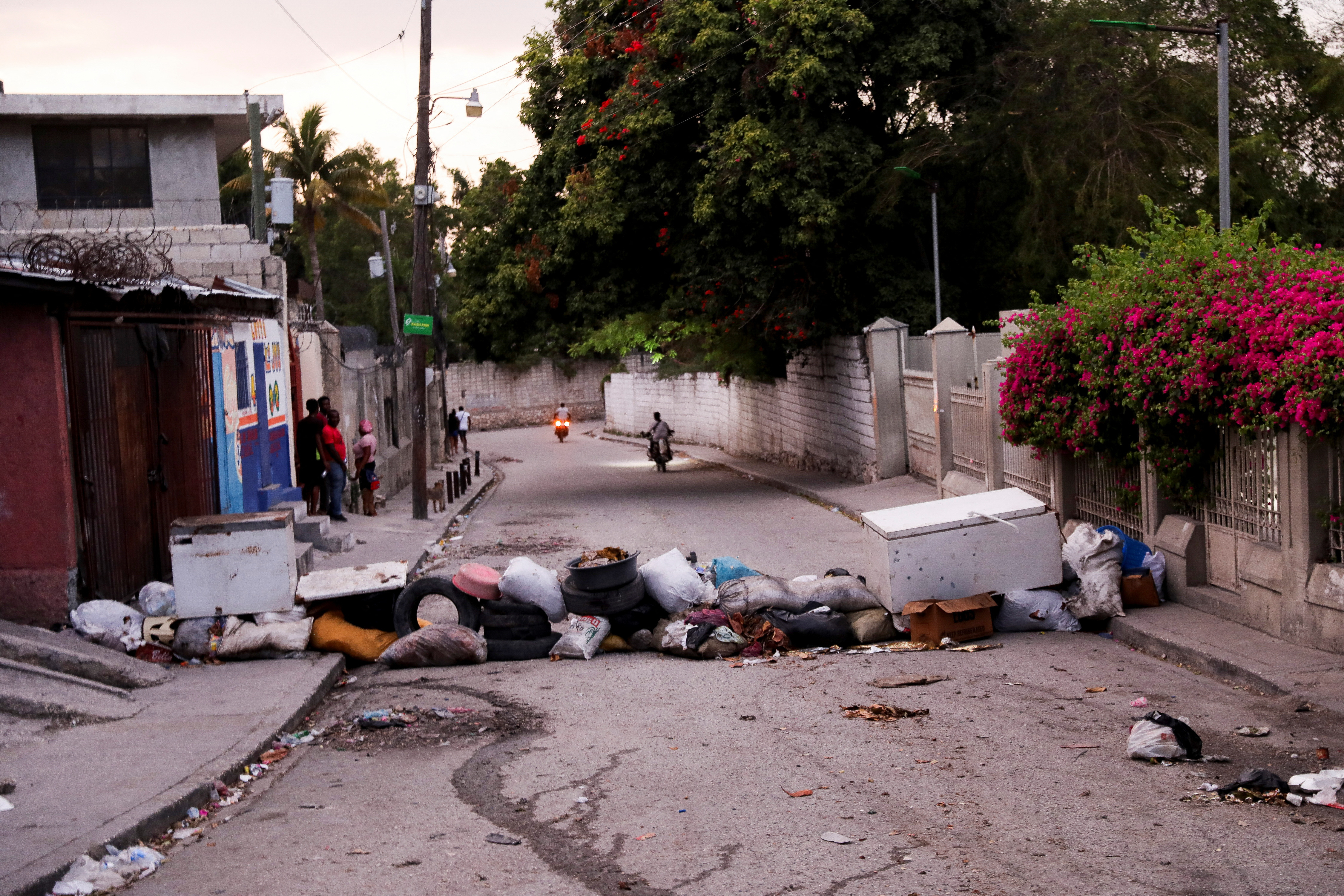 People stand on a barricaded street amid an escalation in gang violence, in Port-au-Prince, Haiti March 20, 2024. 