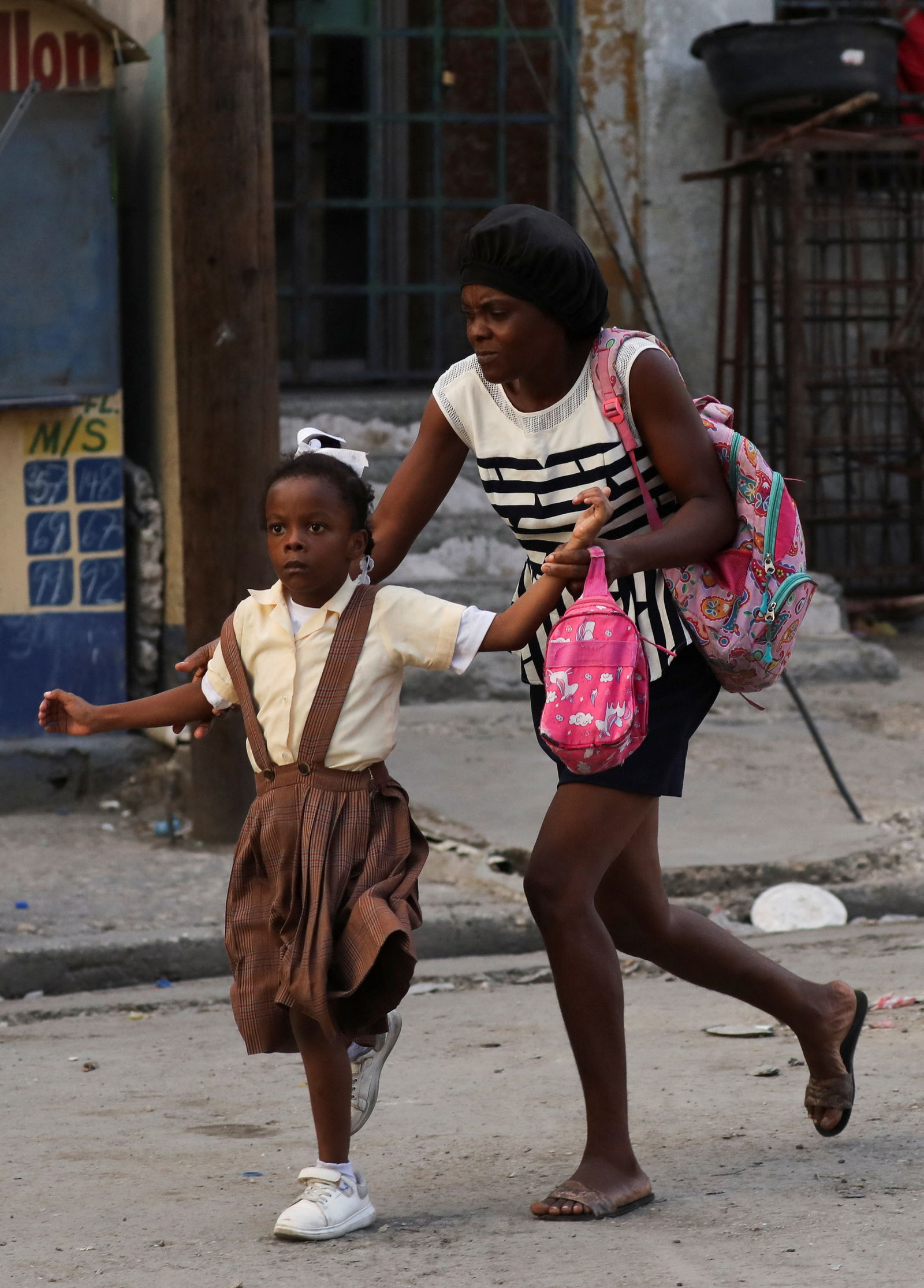 A woman flees with her daughter scared by the sound of gunfire as police confront armed gangs after prominent gang leader Jimmy Cherizier called for Haiti's Prime Minister Ariel Henry's government to be toppled, in Port-au-Prince, Haiti, February 29, 2024. 