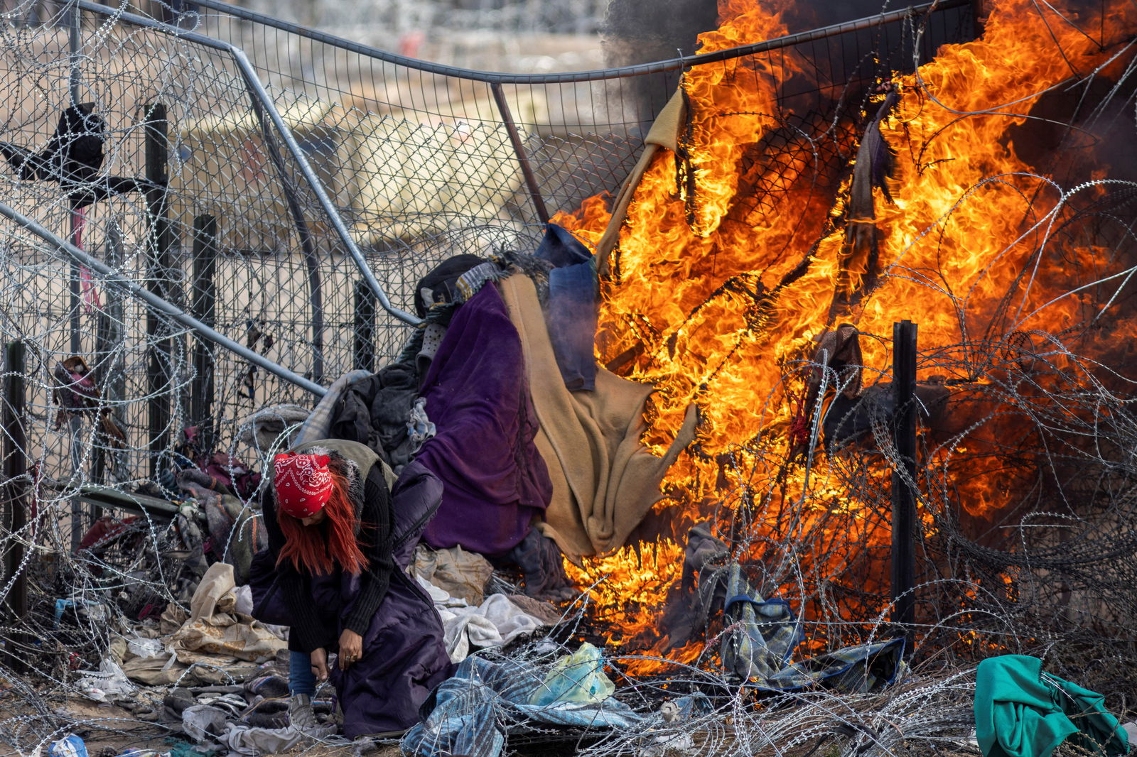 A migrant checks her bag after members of the Texas National Guard burnt clothing used by migrants to break through razor wire and a fence to enter the U.S. to surrender themselves, as SB 4 law that would empower law enforcement authorities in the state to arrest people suspected of illegally crossing the U.S.-Mexico border was temporarily blocked, as seen from Ciudad Juarez, Mexico, March 21, 2024. 