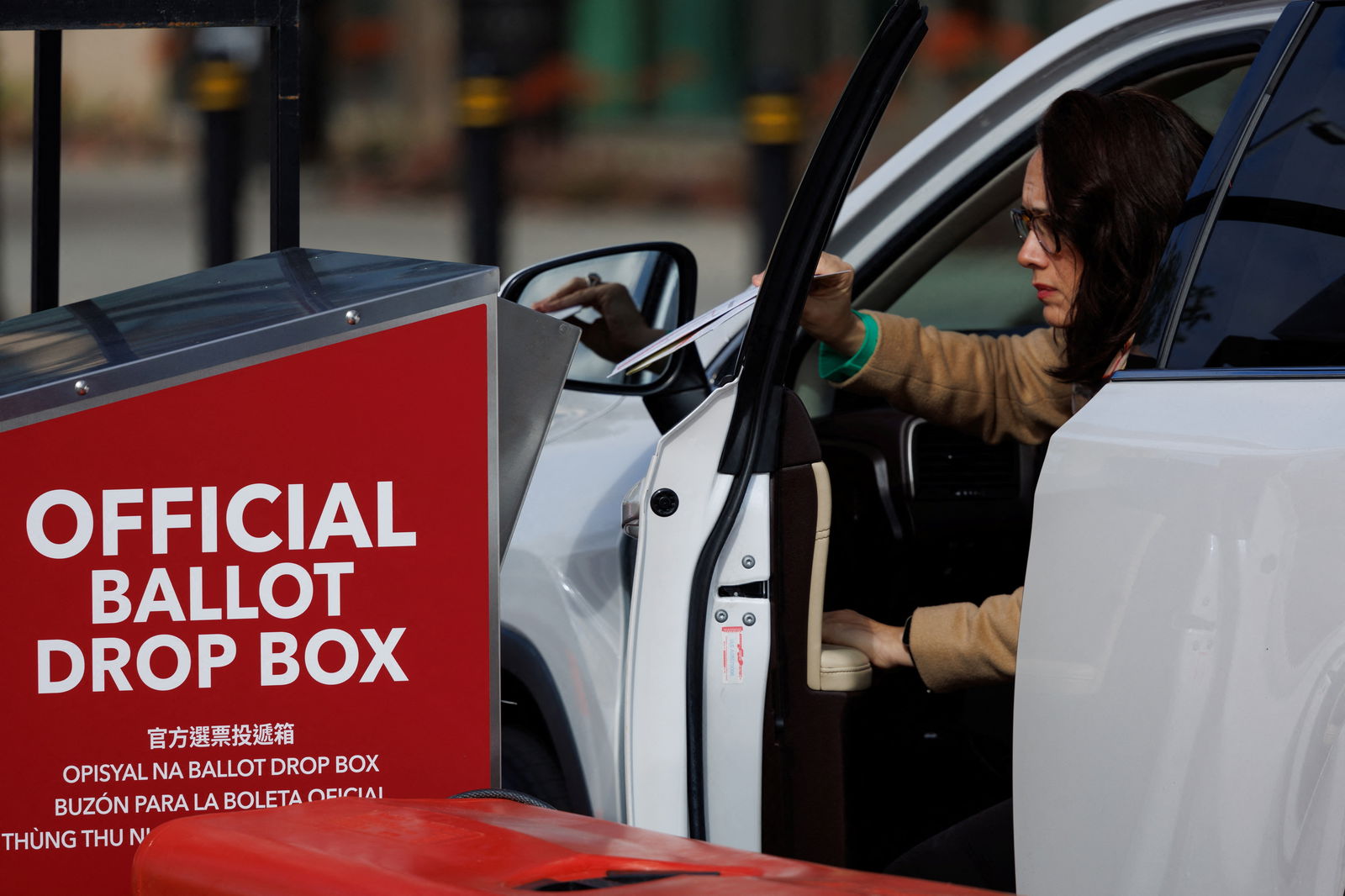 A voter drops a ballot paper into a drop box from her vehicle during the Super Tuesday primary election in San Diego, California U.S., March 5, 2024. 