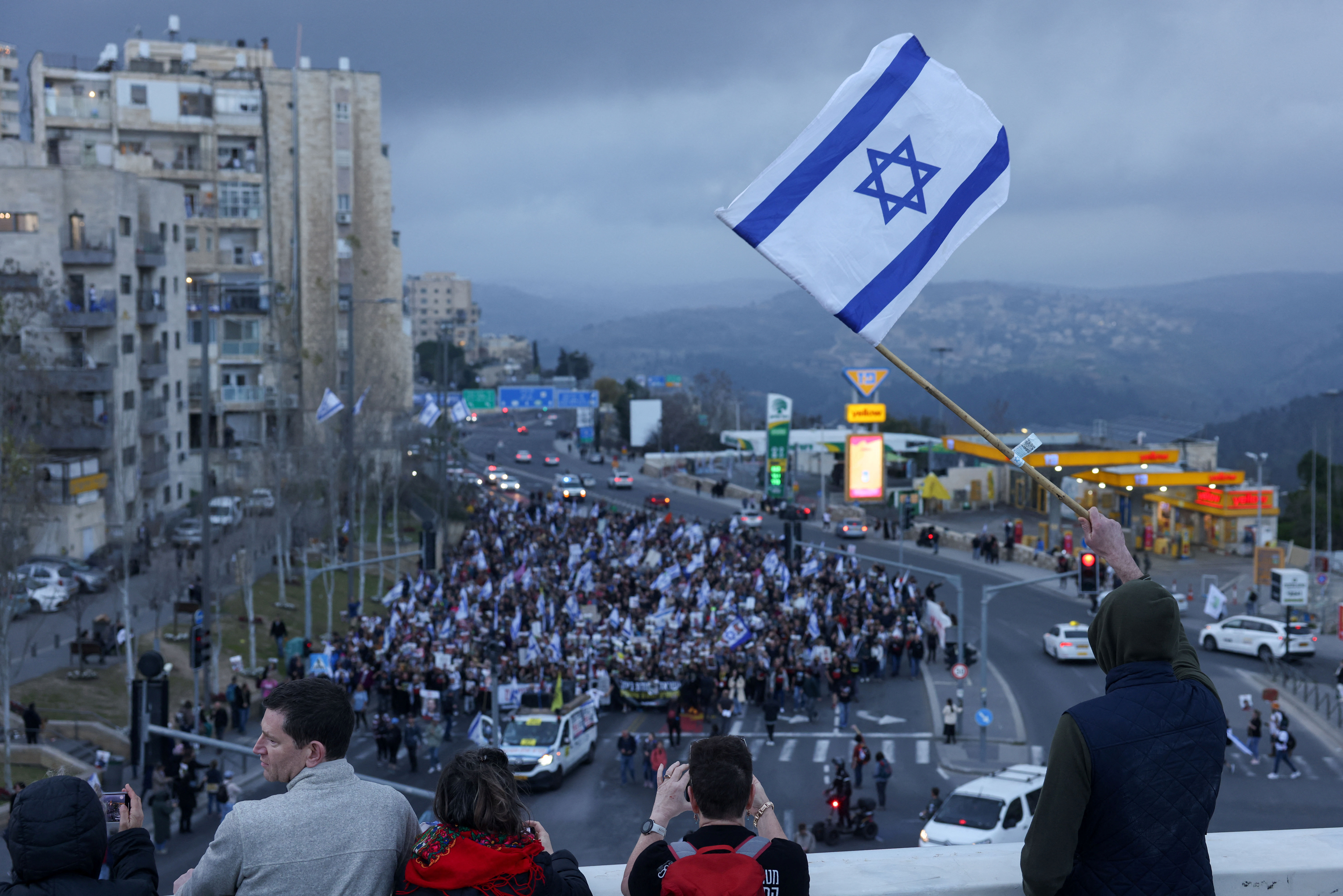 A person waves an Israeli flag as families and supporters of hostages kidnapped in the deadly October 7 attack on Israel by the Palestinian Islamist group Hamas take part in the four day march from Reim to Jerusalem to call for the release of hostages, in Jerusalem, March 2, 2024. 