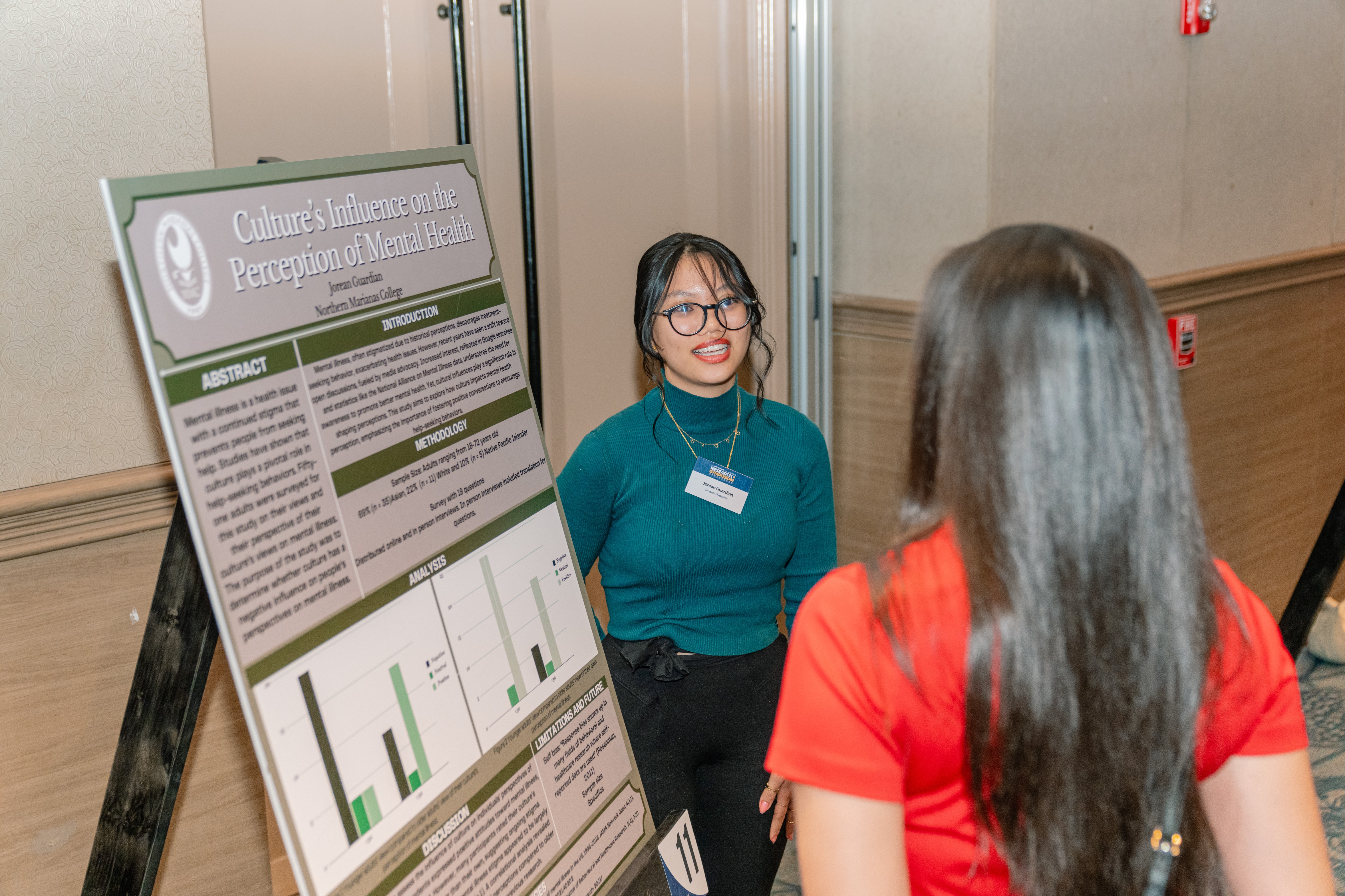 Jorean Guardian, an NMC student and Proa Pathway scholar, presents her research to a symposium attendee.