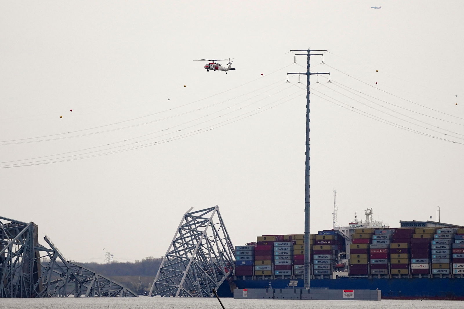 A helicopter flies over the Dali cargo vessel which crashed into the Francis Scott Key Bridge causing it to collapse, in Baltimore, Maryland, U.S., March 26, 2024. 