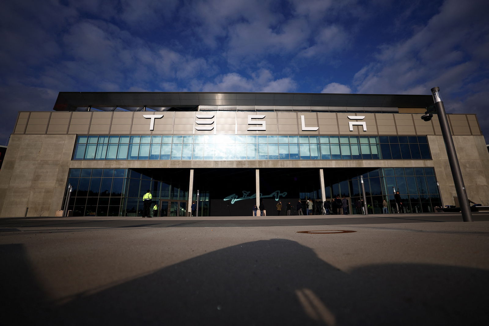 Members of the media stand outside the building of Tesla's production plant in Gruenheide outside Berlin, Germany, March 5, 2024, after the site lost power following a suspected arson attack on a nearby pylon. 