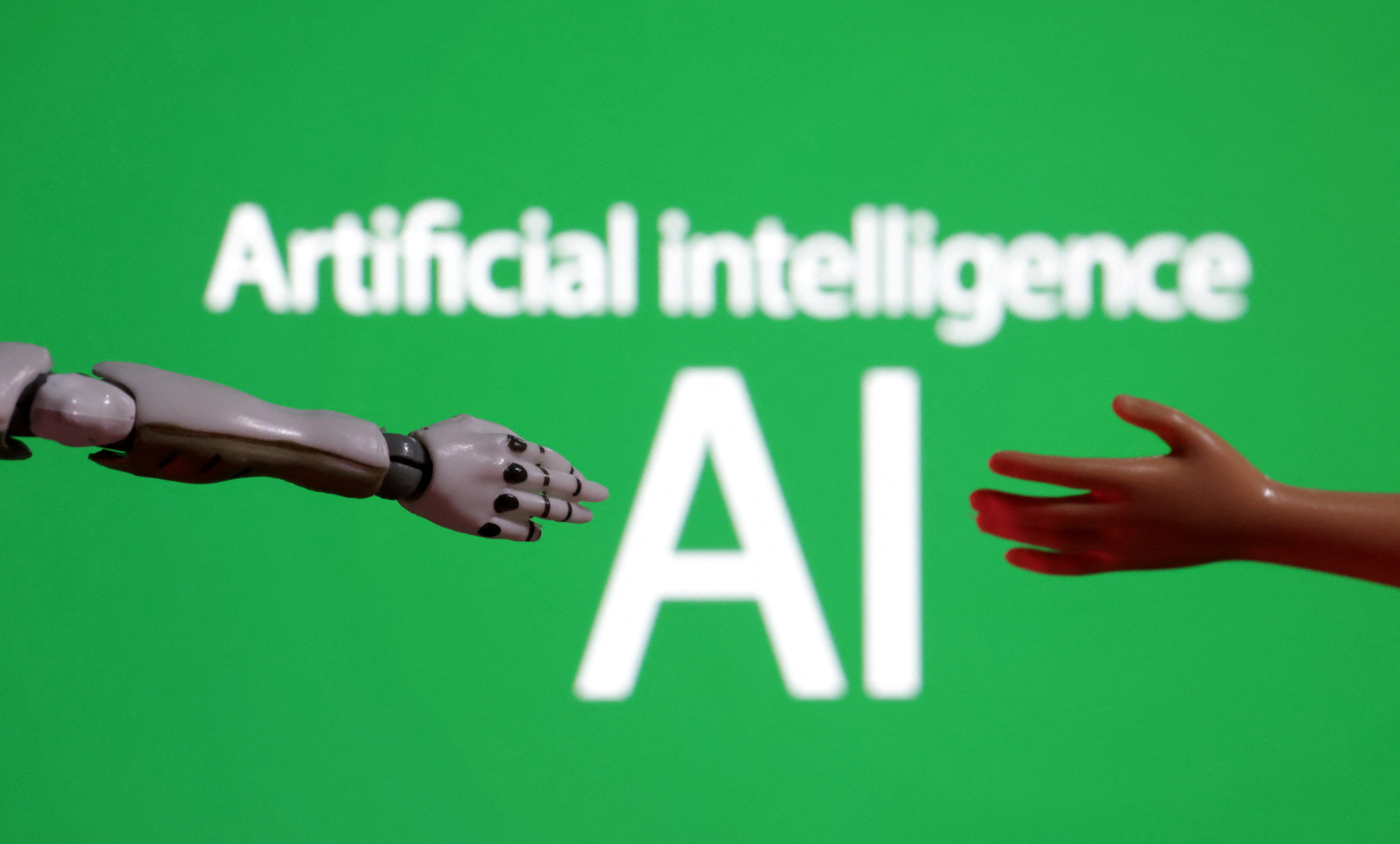 Words reading "Artificial intelligence AI", miniature of robot and toy hand are pictured in this illustration taken December 14, 2023. 