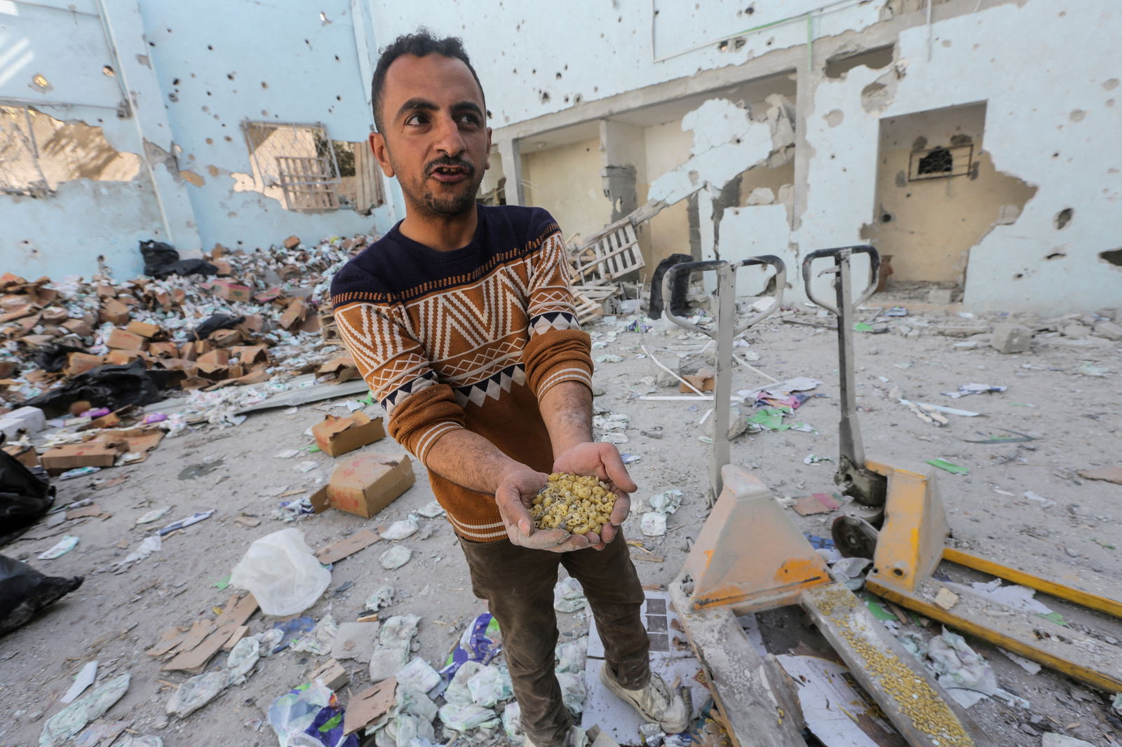 A Palestinian holds uncooked pasta at the site of an Israeli strike on an aid warehouse, amid the ongoing conflict between Israel and Hamas, in Al-Nuseirat refugee camp in the central Gaza Strip March 14, 2024. 