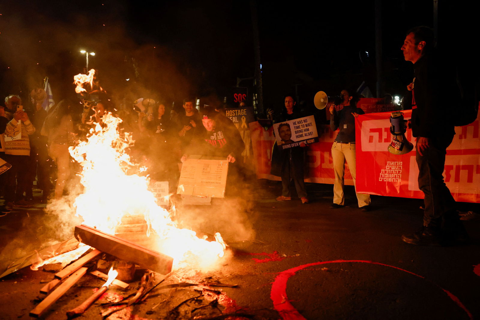 Demonstrators light up a fire outside the Israeli Ministry of Defense during a protest calling for the release of hostages kidnapped in the deadly October 7 attack on Israel by the Palestinian Islamist group Hamas from Gaza, in Tel Aviv, Israel, March 14, 2024. 