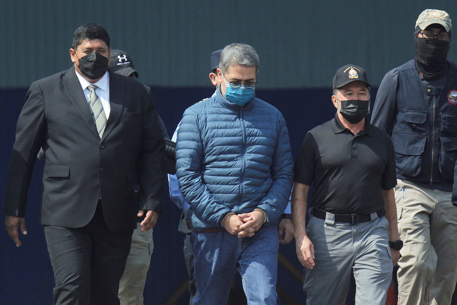 FILE PHOTO: Honduras former President Juan Orlando Hernandez is escorted by authorities as he walks towards a plane of the U.S. Drug Enforcement Administration (DEA) for his extradition to the United States, to face a trial on drug trafficking and arms possession charges, at the Hernan Acosta Mejia Air Force base in Tegucigalpa, Honduras April 21, 2022. 
