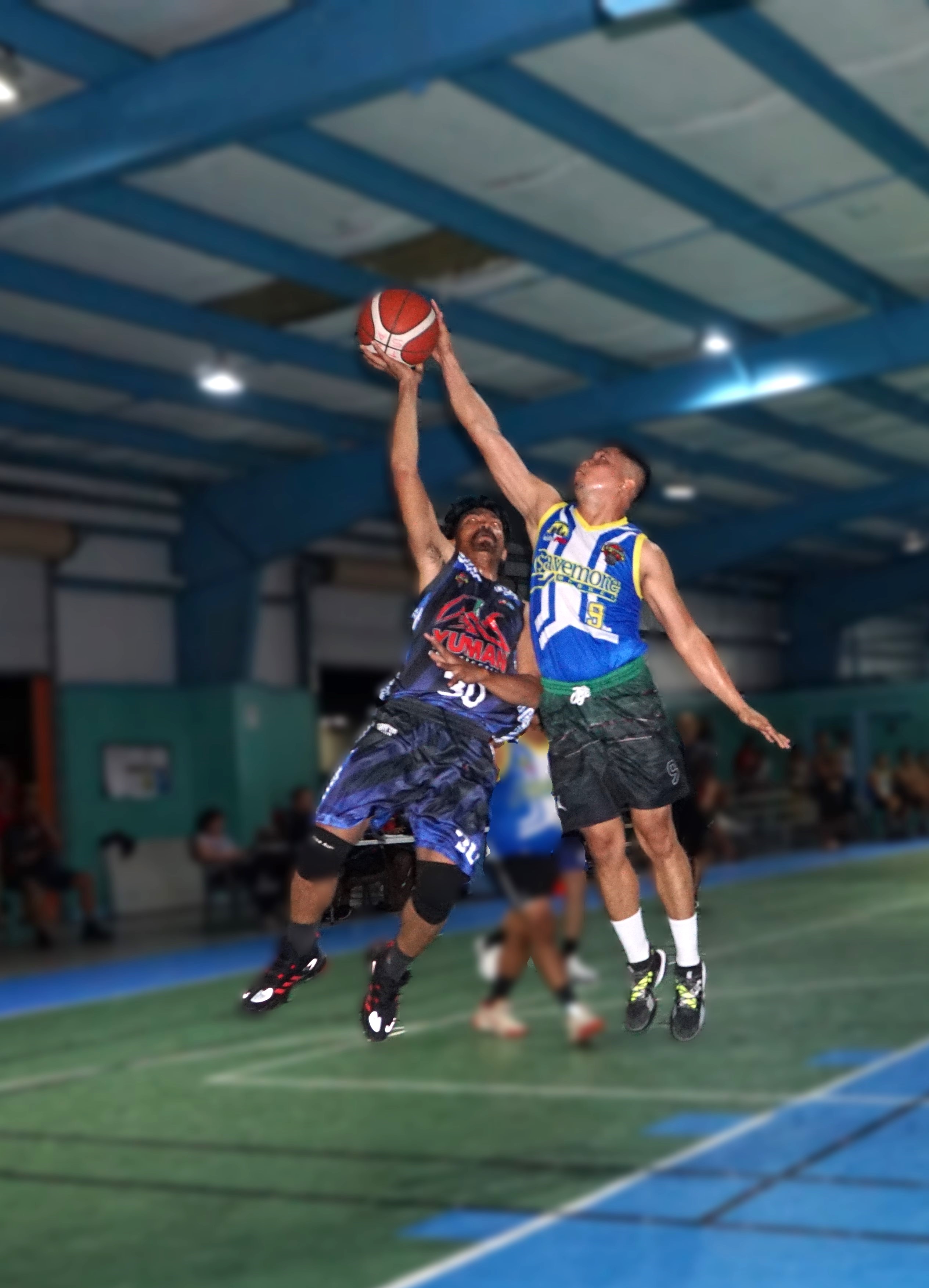 Savemore's Julius Domine denies the shot attempt of Yuman's Raymond Atencio during a Legends Sports Association Invitational Basketball League game at the TSL Sports Complex.