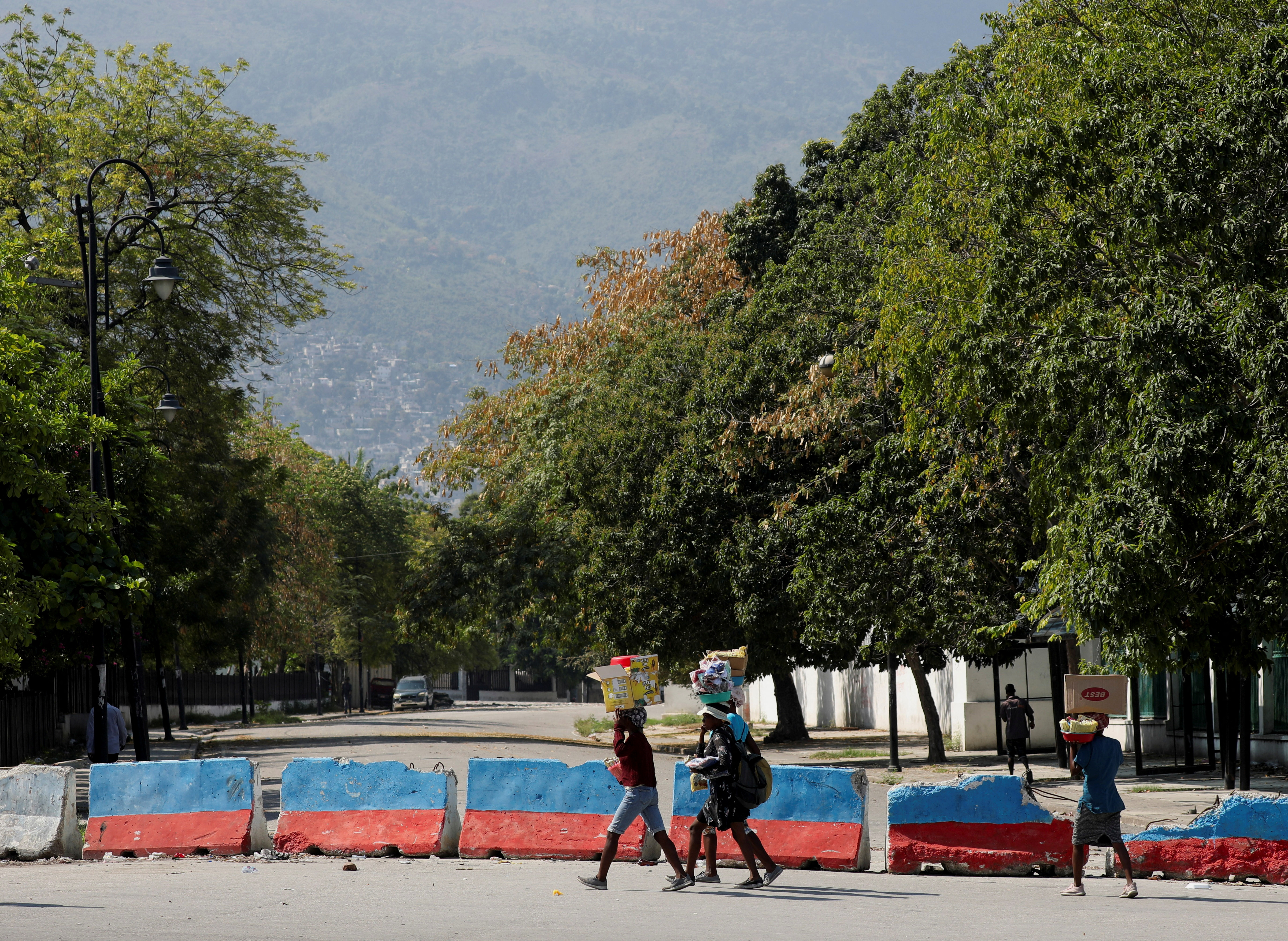 Street vendors carry goods for sale as they walk near the Presidential Palace after Haiti's Prime Minister Ariel Henry pledged to step down following months of escalating gang violence, in Port-au-Prince, Haiti March 12, 2024. 