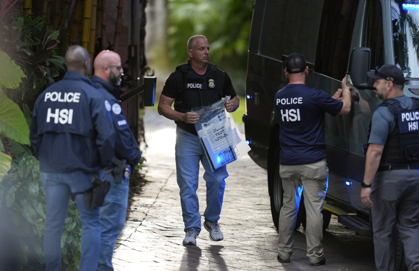 A law enforcement agent carries a bag of evidence to a van as federal agents stand at the entrance to a property belonging to rapper Sean “Diddy” Combs, Monday, March 25, 2024 on Star Island in Miami Beach, Fla.