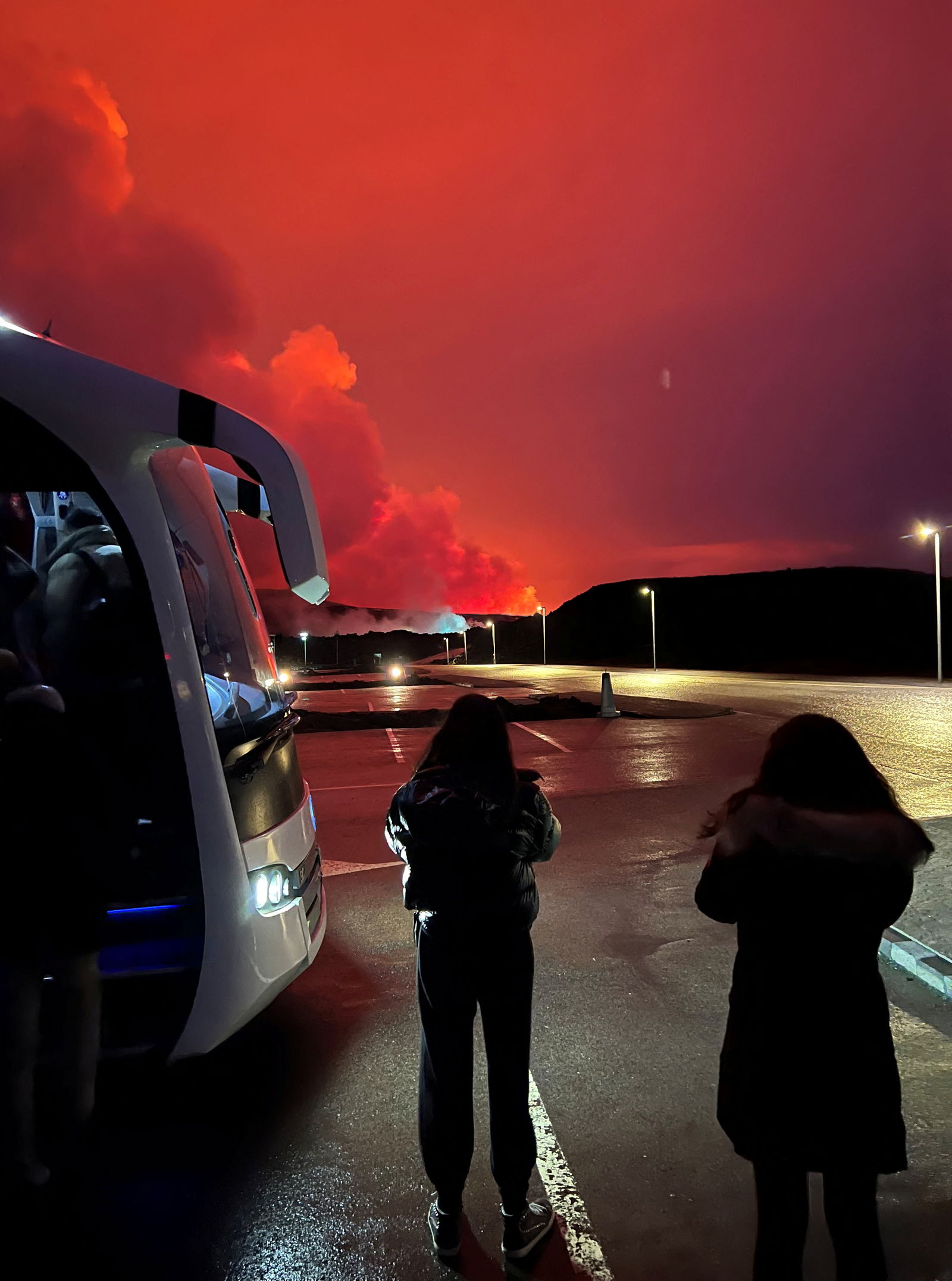 People who are being evacuated stand by a bus as a volcano erupts, in Grindavik, Iceland, March 16, 2024, in this picture obtained from social media. 