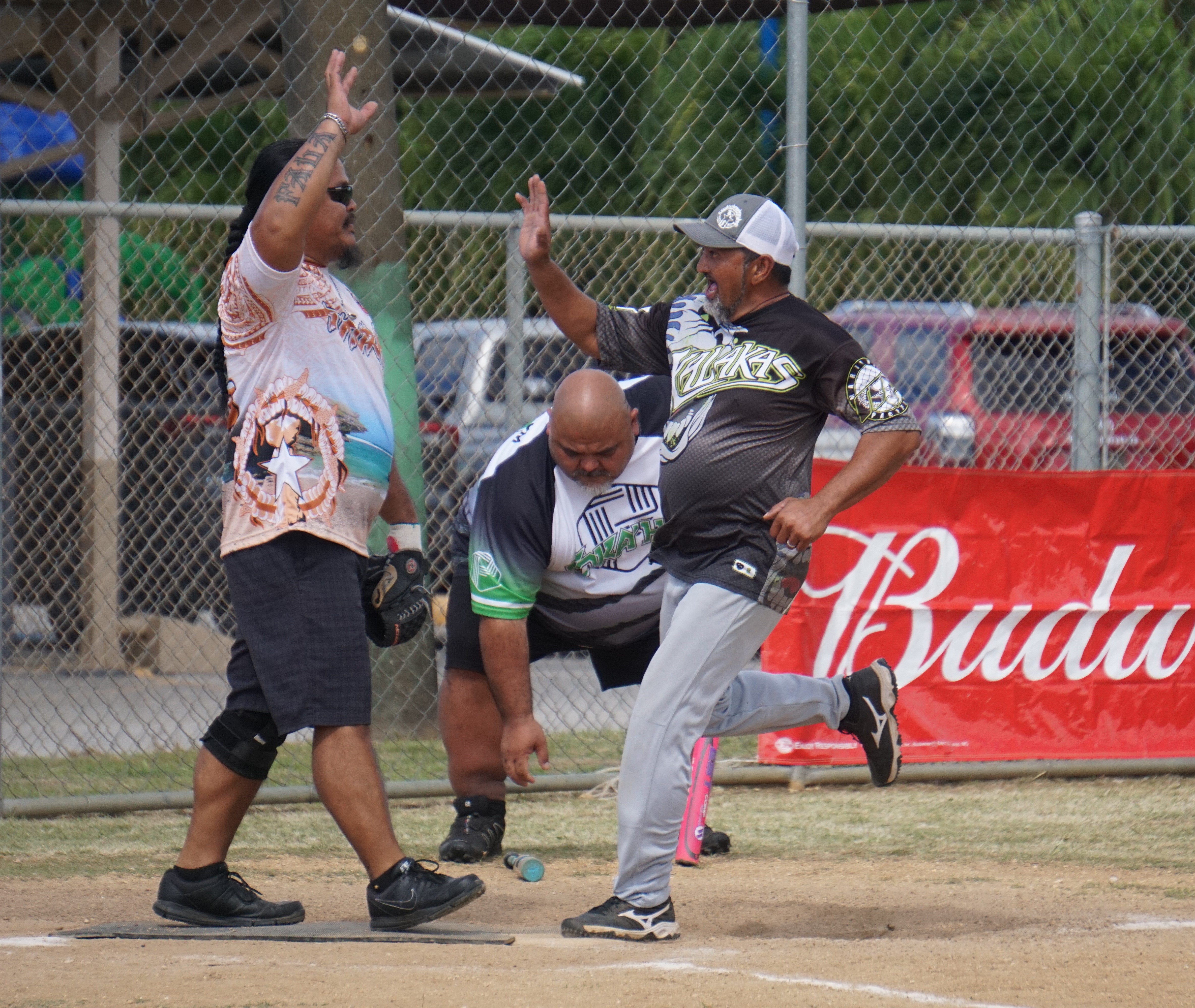 Tokahao’s Manny Villagomez and his teammate celebrate after scoring a run during a Budweiser Belau Amateur Softball League game at the Dandan baseball field.