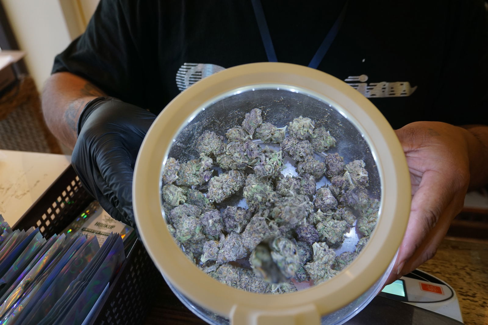 Courtney Nakazato holds a bowlful of Hawaiian Rain flowers under a magnifying glass at The Hook Up. According to budtender Mikel Johnson​, Hawaiian Rain makes him feel "relaxed and no stress." 