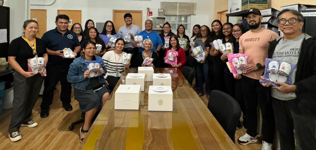 Karidat Executive Director Lauri Ogumoro and FSM Recycling owner Mike Jang pose for a photo with Karidat staff and members of other community groups as they hold the brand new pairs of footwear donated by Jang at the Karidat office in Dandan last month.