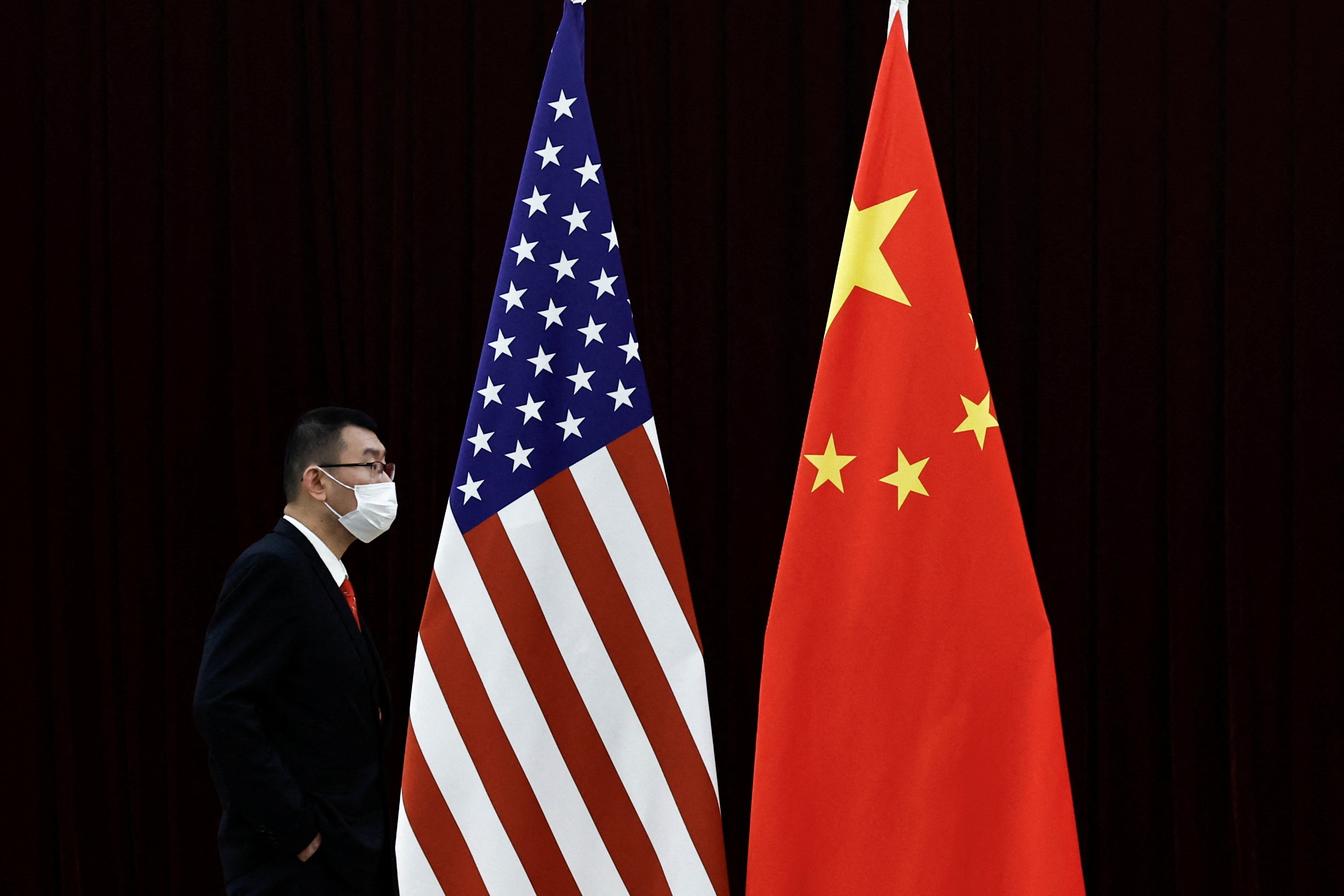A man walks past the national flags of China and the U.S. before a meeting between China's Vice Premier He Lifeng and U.S. Treasury Secretary Janet Yellen at the Guangdong Zhudao Guest House, in Guangzhou, Guangdong province, China, April 6, 2024.
