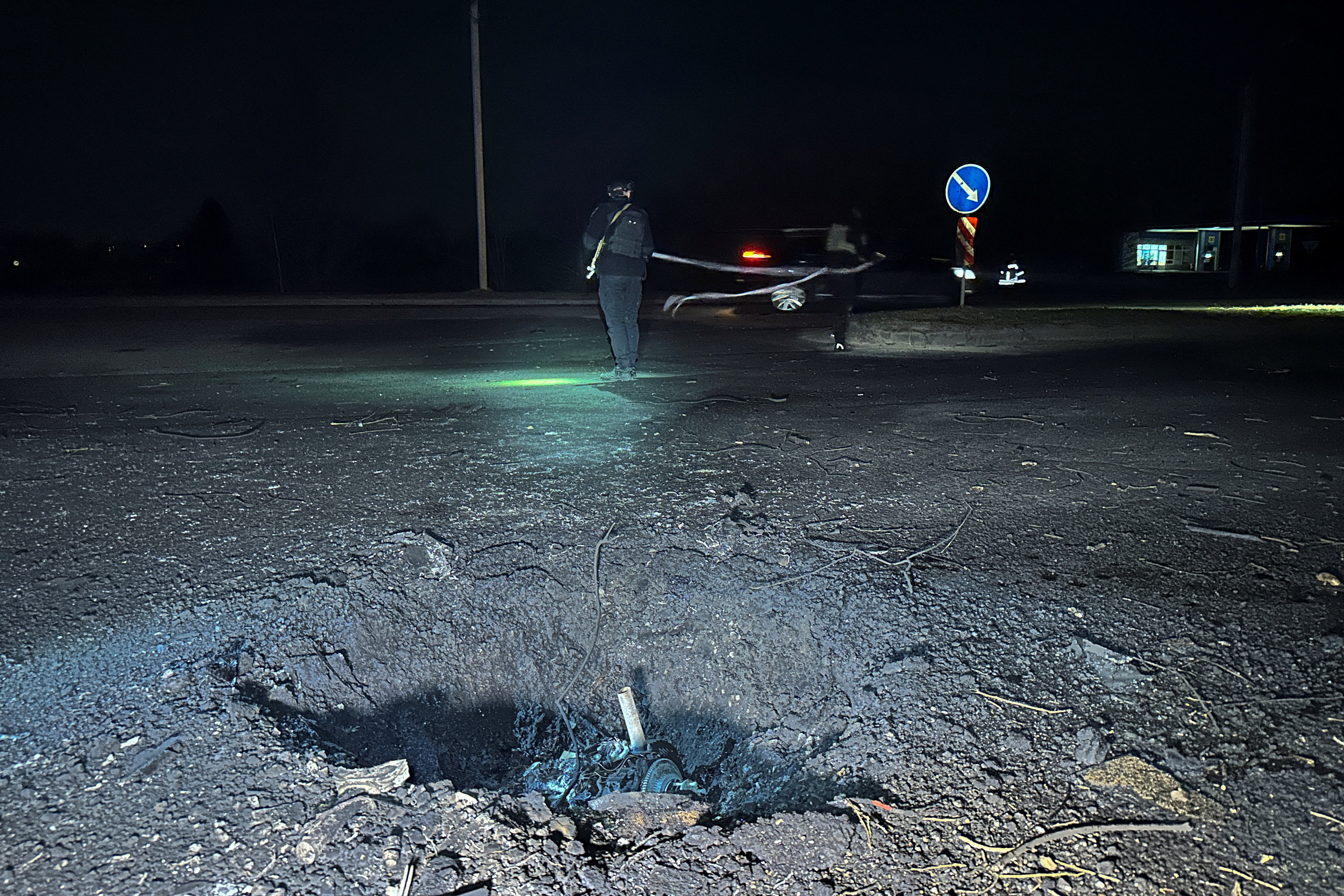FILE PHOTO: Police officers work next to a crater that appeared after a Russian drone strike, amid Russia's attack on Ukraine, in Kharkiv, Ukraine March 26, 2024. 