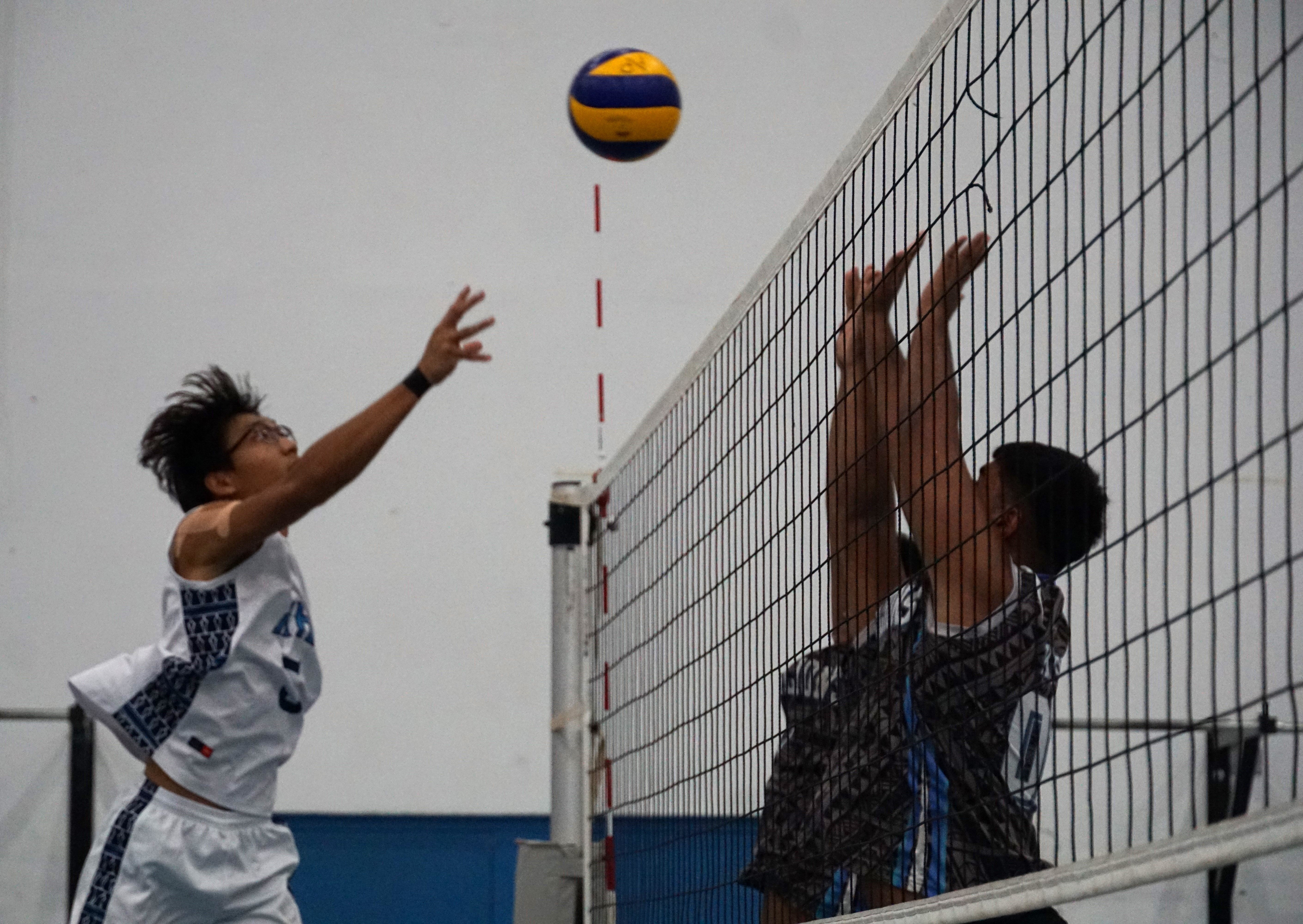 MHS' Juruel Magtalas tips the ball over two Tinian defenders during a boys high school division game of the NMIVA-PSS Interscholastic Volleyball League SY23-24 at the MHS gym on Friday.