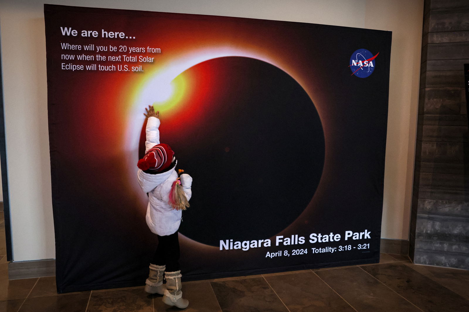 A child touches a NASA countdown display, ahead of the Solar Eclipse that will take place across parts of the United States and Canada on April 8, at Niagara Falls, New York, U.S., April 5, 2024. 