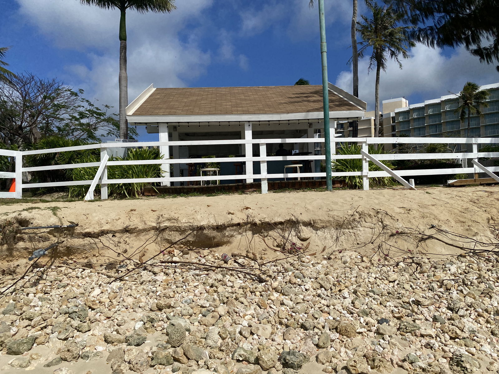 The beachside bar of the Hyatt Regency Saipan sits behind a white fence that marks the area where Hyatt's private property ends and public land begins.​