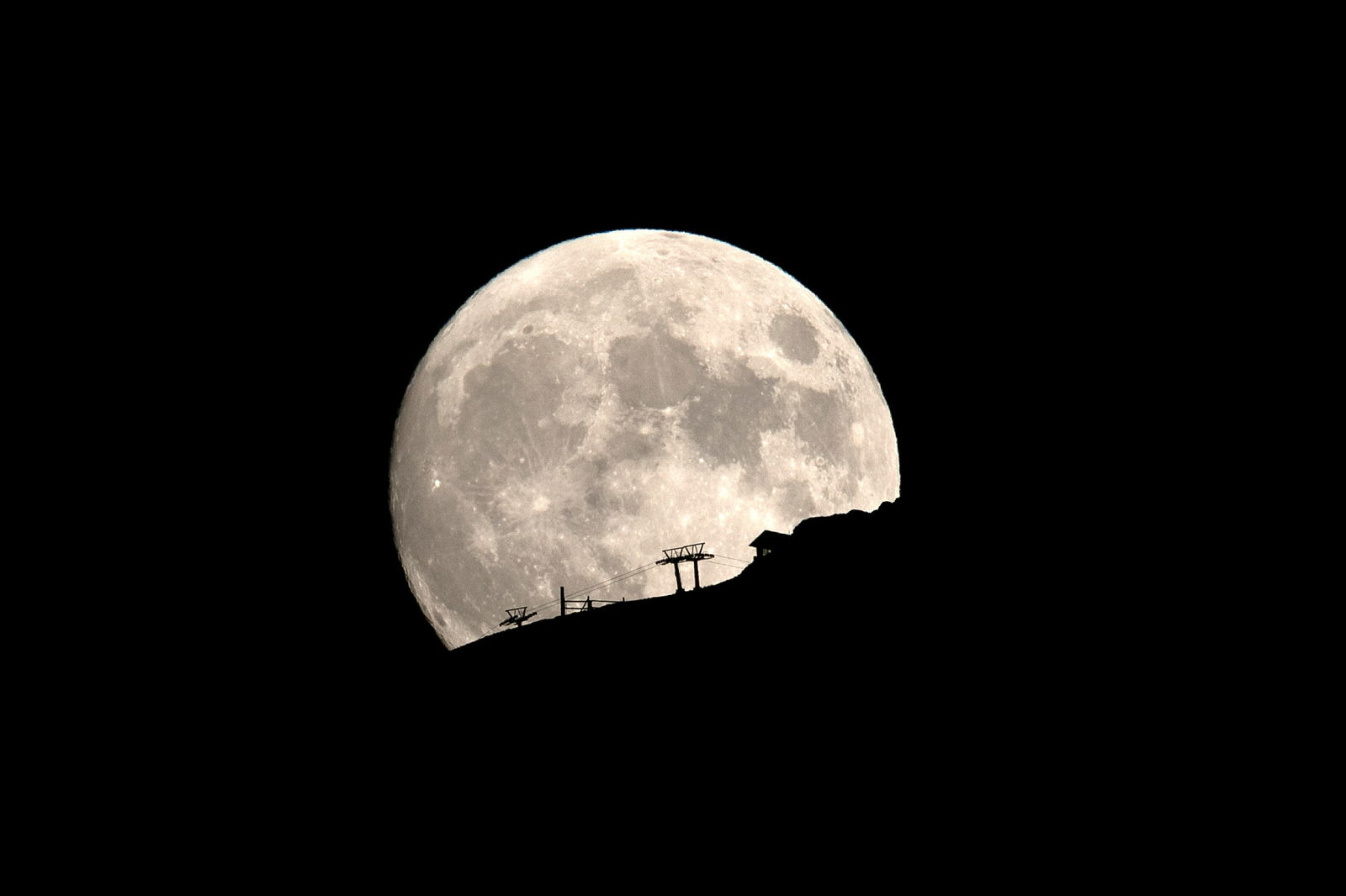 FILE PHOTO: A ski lift at the Kalavrita ski centre on Mount Helmos is silhouetted as the moon rises near the town of Kalavrita, Greece, August 14, 2019. 