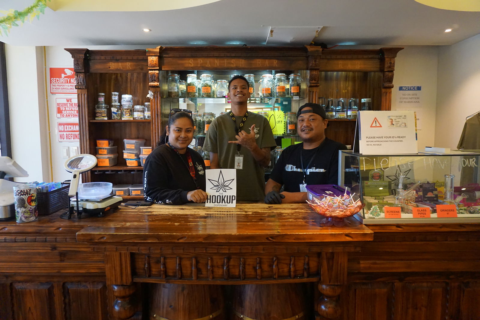 From left, budtenders Nish Wabol, Mikel Johnson, and Courtney Nakazato pose at the store counter of The Hook Up on April 18