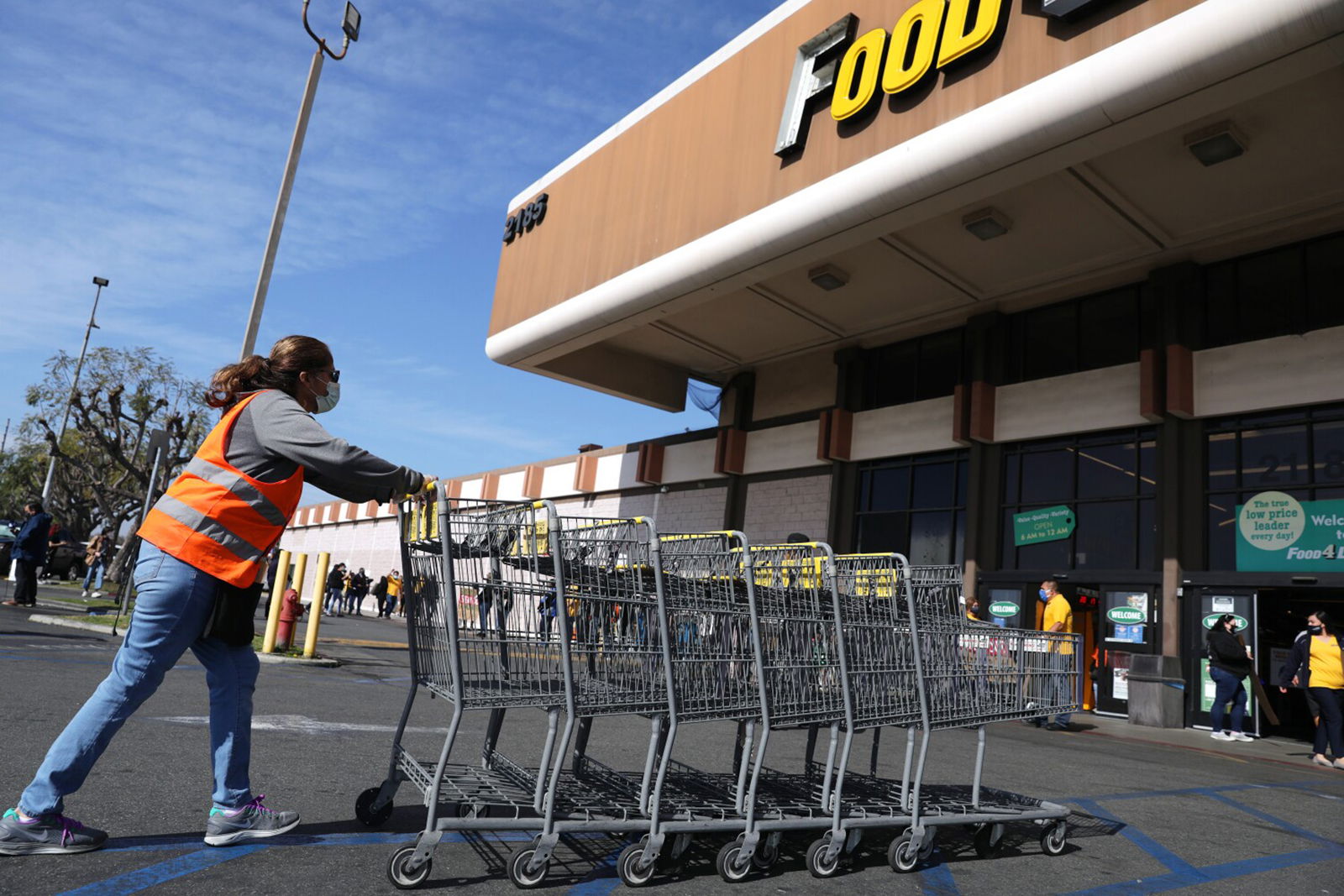 A grocery worker collects carts outside of the Food 4 Less on South Street in North Long Beach, California on Feb. 3, 2021. (Christina House/Los Angeles Times/TNS)
