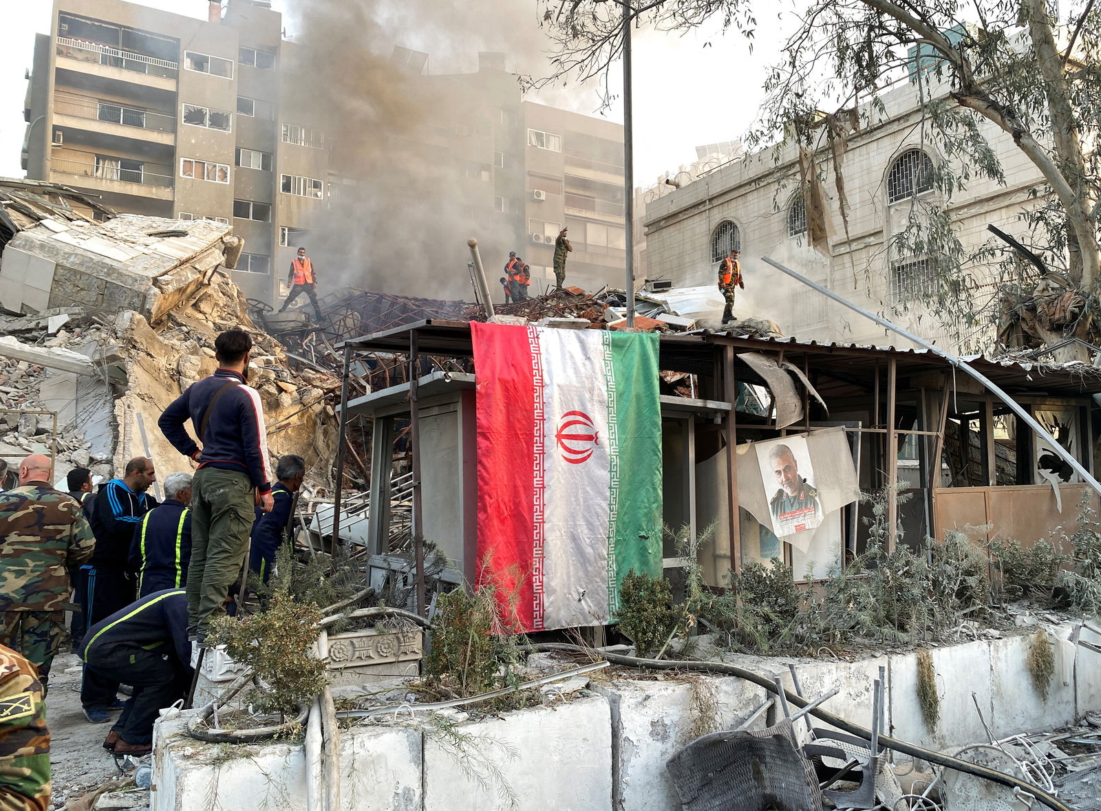 An Iranian flag hangs as smoke rises after what the Iranian media said was an Israeli strike on a building close to the Iranian embassy in Damascus, Syria April 1, 2024. 