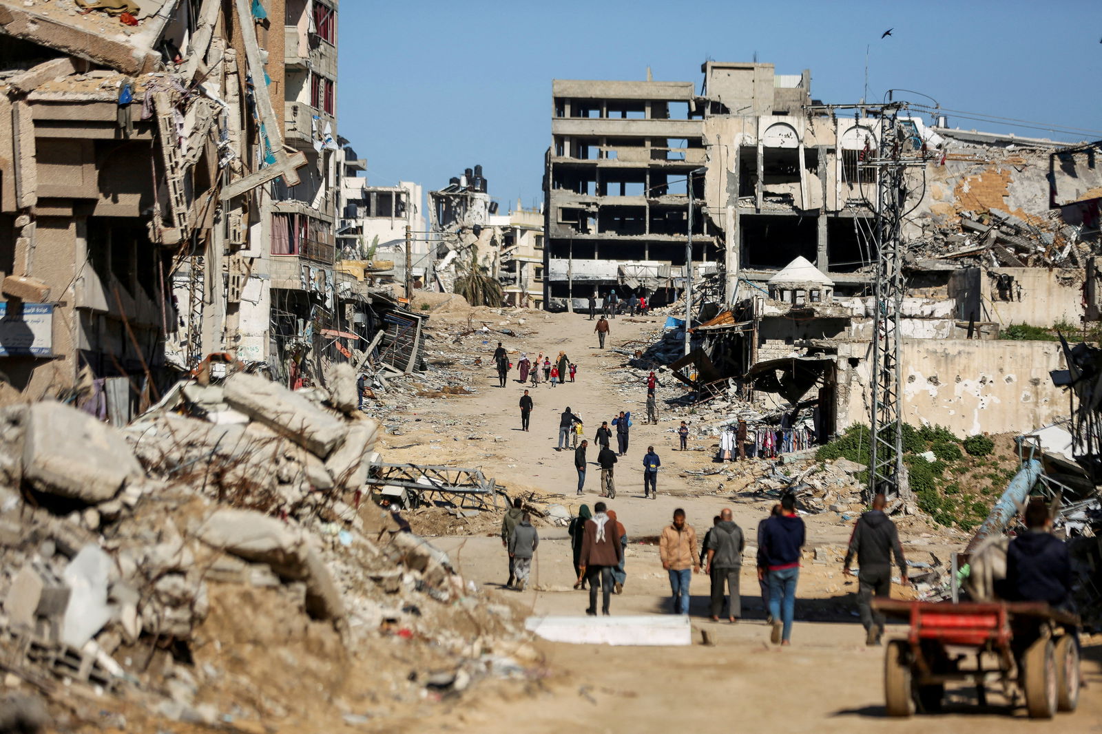 FILE PHOTO: Palestinians walk past the ruins of houses destroyed during Israel's military offensive, amid the ongoing conflict between Israel and Hamas, in Gaza City, March 20, 2024. 
