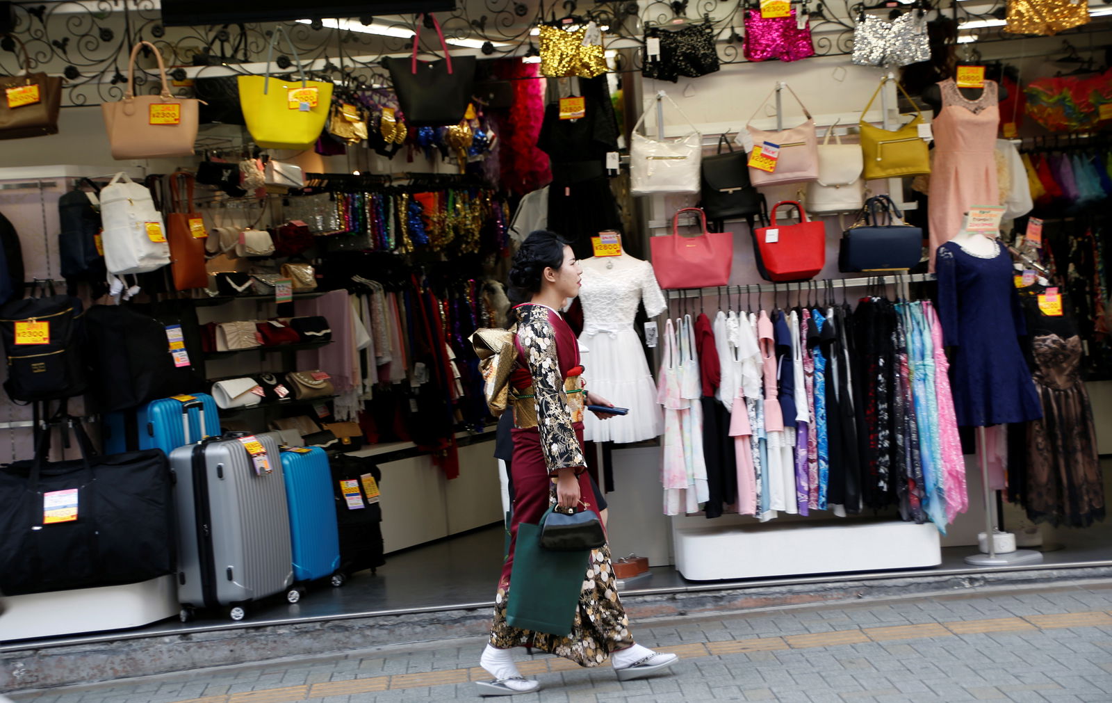 FILE PHOTO: A woman in a kimono walks past a shop in a shopping district in Tokyo, Japan March 23, 2017. Picture taken on March 23, 2017. 