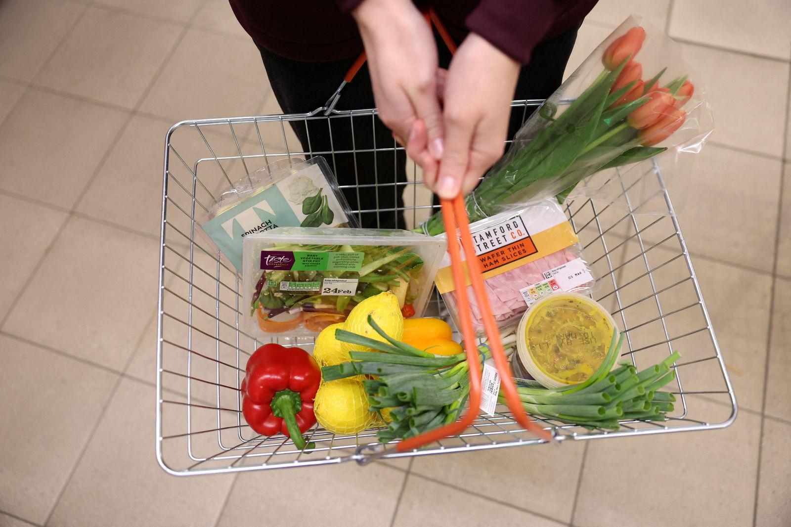 FILE PHOTO: A customer carries a basket filled with food inside a Sainsbury?s supermarket in Richmond, West London, Britain February 21, 2024. 