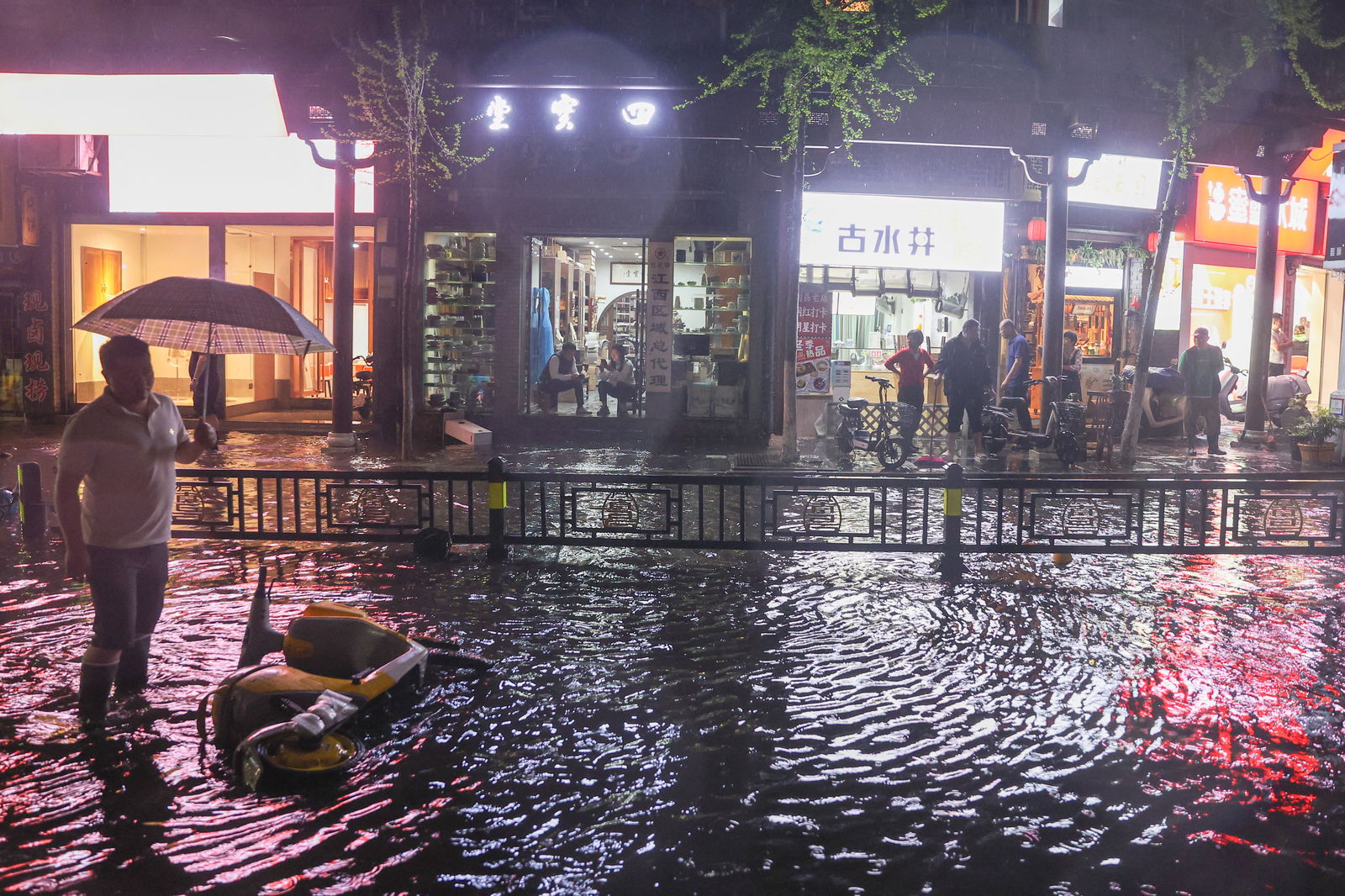 People stand on a flooded street as storms brought rains and hailstones to Nanchang, Jiangxi province, China April 2, 2024. 