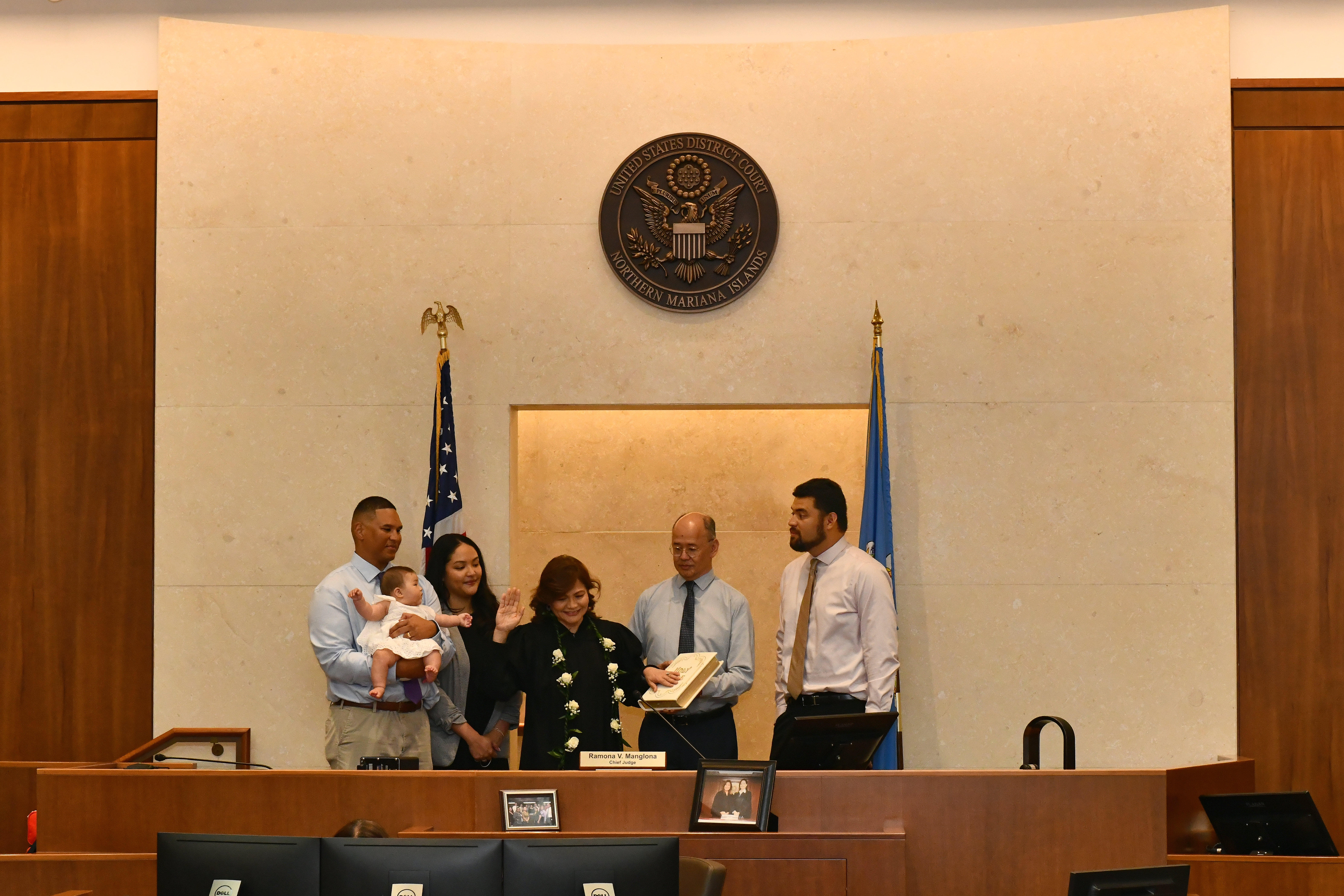 District Court for the NMI Chief Judge Ramona V. Manglona takes the oath of office administered virtually by District Court of Guam Chief Judge Frances M. Tydingco-Gatewood. Judge Manglona’s husband, Justice John A. Manglona, holds the Bible as their children, Savana, Dencio, far right, son-in-law Jalen, far left, and granddaughter Kaia Jay look on.