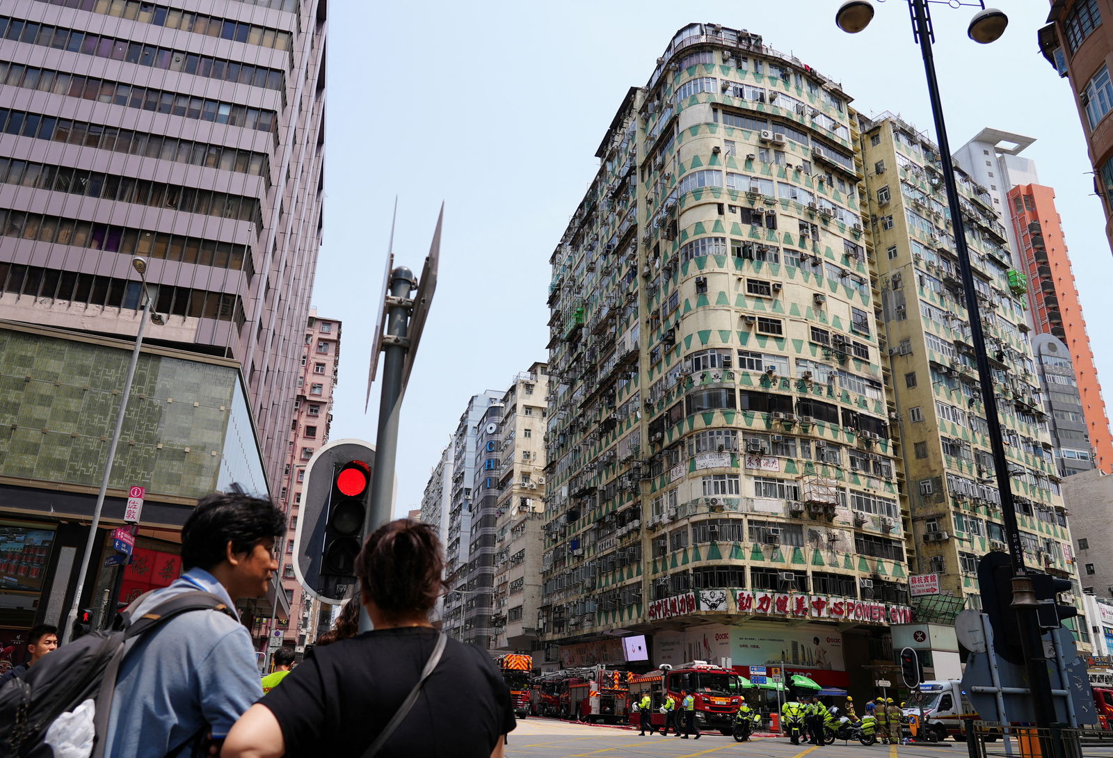 People look on near the residential building where a fire broke out in a gym, in Kowloon district, in Hong Kong, China April 10, 2024. 