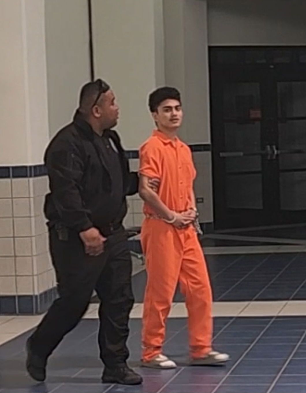 Leroy Villagomez Jr. enters the local courthouse while escorted by a Corrections officer.