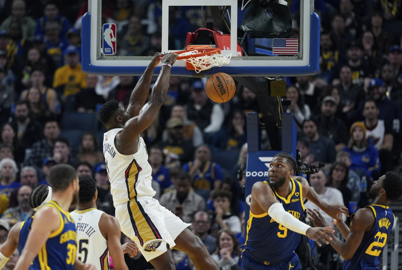 New Orleans Pelicans forward Zion Williamson dunks next to Golden State Warriors center Kevon Looney during the first half of an NBA game Friday, April 12, 2024 in San Francisco.