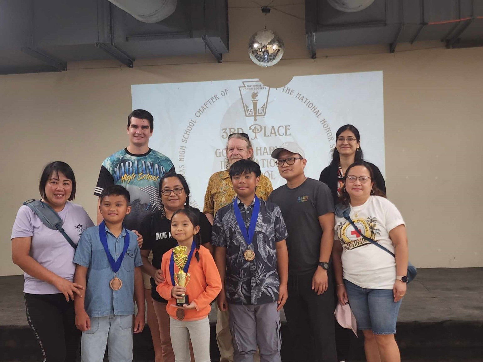 Golden Harvest International School students Gabriel Frederick T. Cariaso, Ethan James B. Bahillo, and Nathalia Reana B. Dagos finished third in the 26th Academic Challenge Bowl at Marianas High School on Saturday, April 20, 2024. Also in photo are the students’ coach, adviser, school principal and the competition judges.