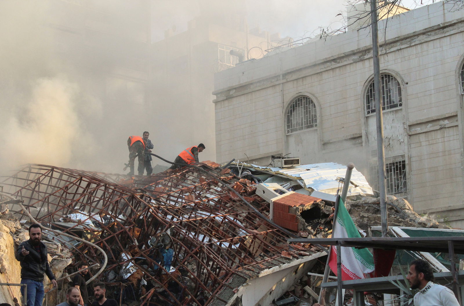 Members of the civil defense stand near a damaged site after what Syrian and Iranian media described as an Israeli air strike on Iran's consulate in the Syrian capital Damascus April 1, 2024. 