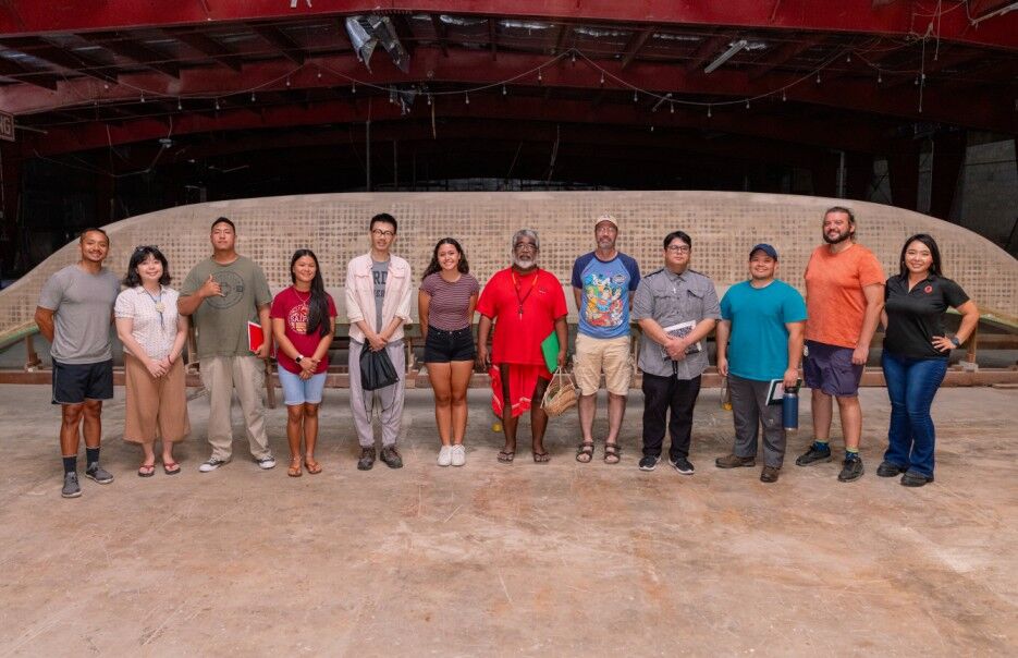 Nine students of the first navigation class offered by the NMC Community Development Institute and 500 Sails pose in front of a canoe under construction at the 500 Sails Boatyard. Lianalynn Muna is 4th from left, Yang Jiao is 5th from left, and Tiana Torres is 6th from left.